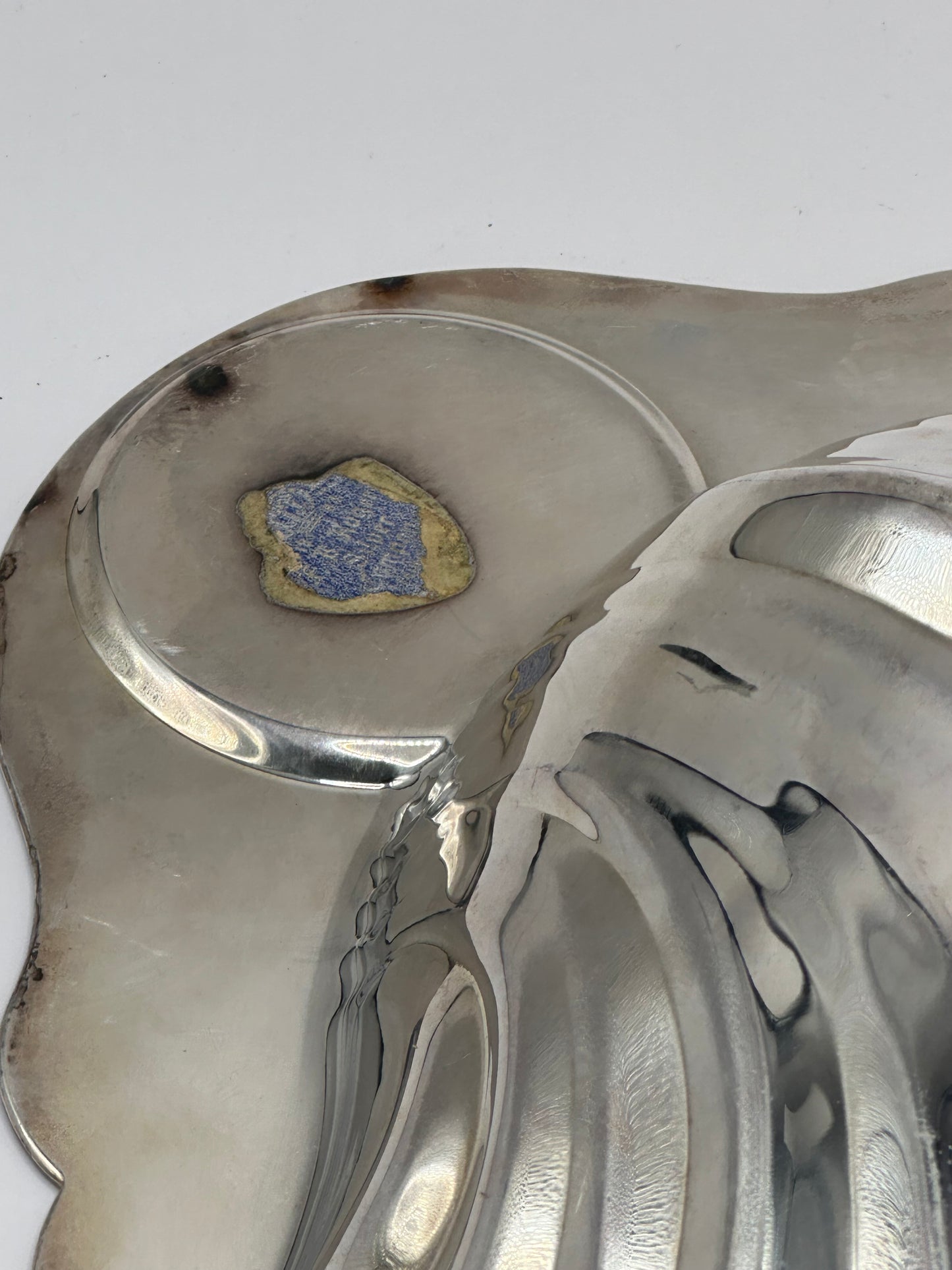 Close-up of the Rogers shell server underside showing tarnish spots and remnants of a blue paper label