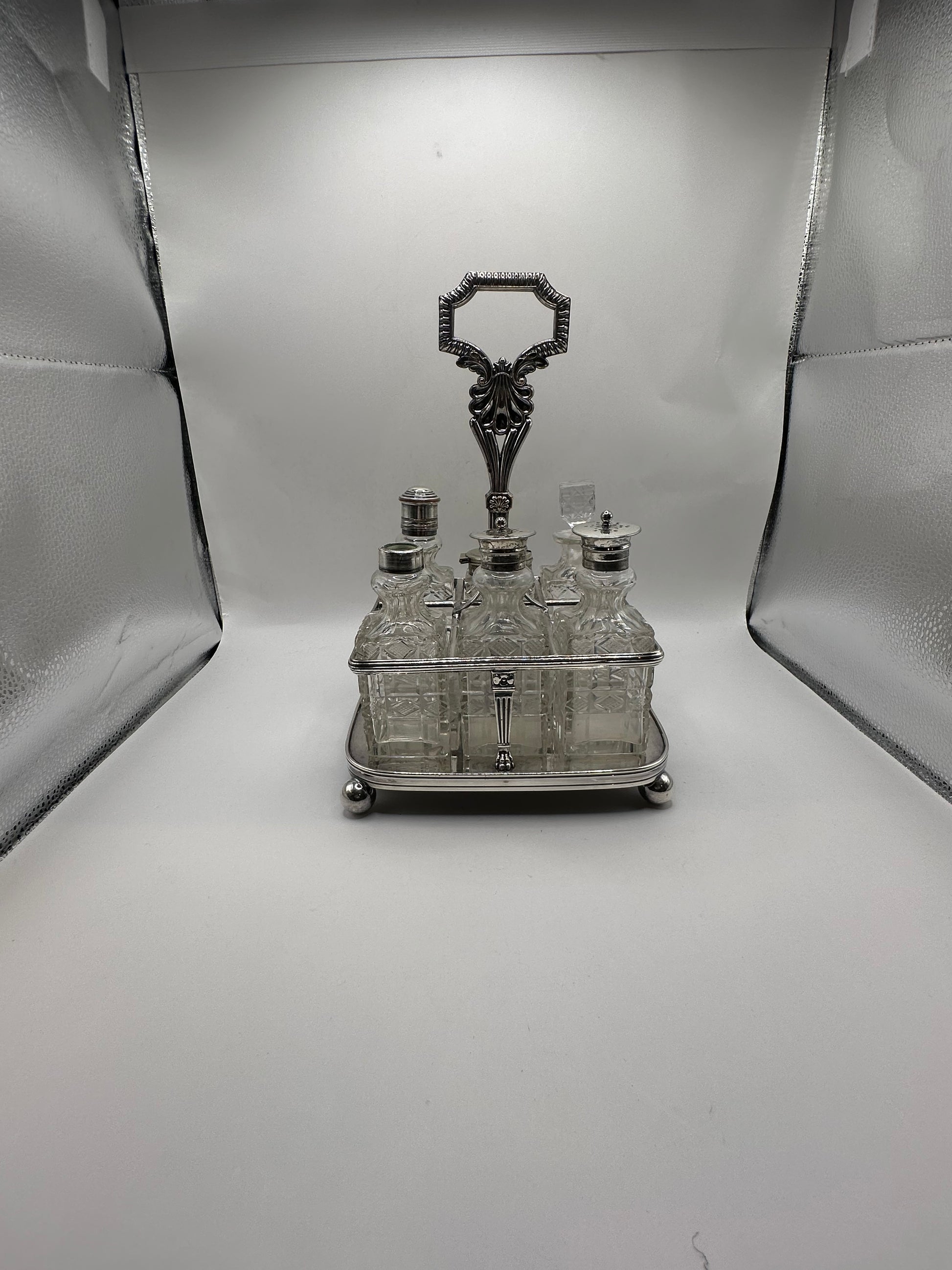 Antique cruet set fully assembled, all cut-glass bottles seated in the silver caddy, front view