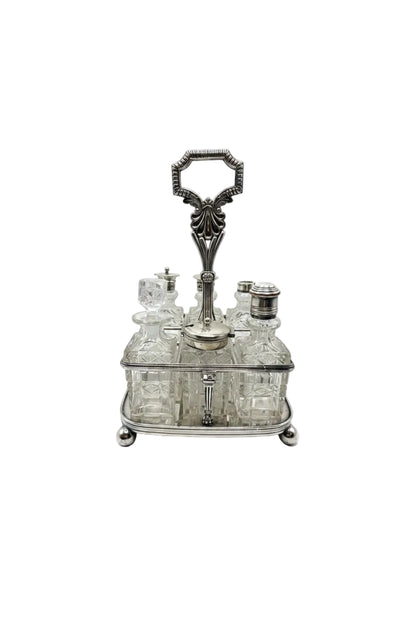 Antique 7-piece cruet set, cut-glass bottles in a silver stand with ornate loop handle, front view