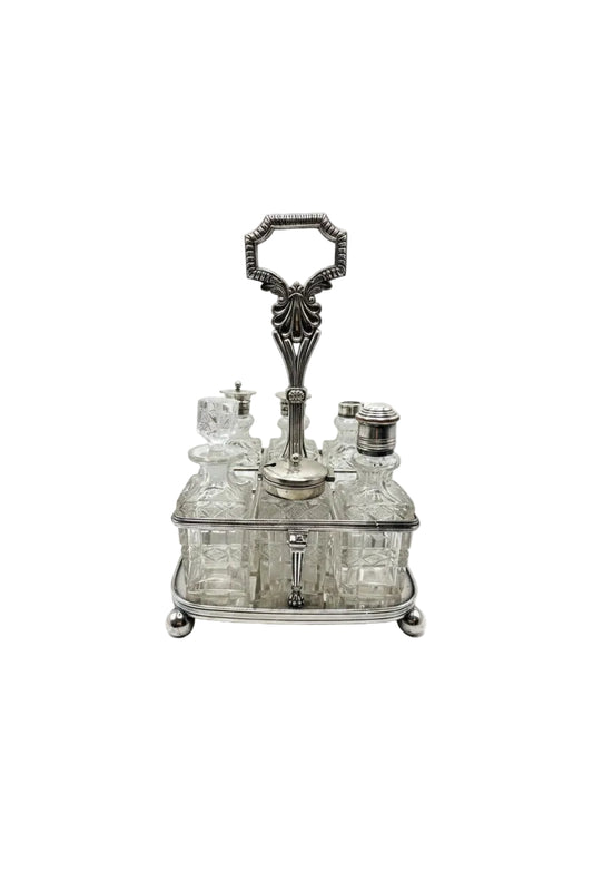 Antique 7-piece cruet set, cut-glass bottles in a silver stand with ornate loop handle, front view