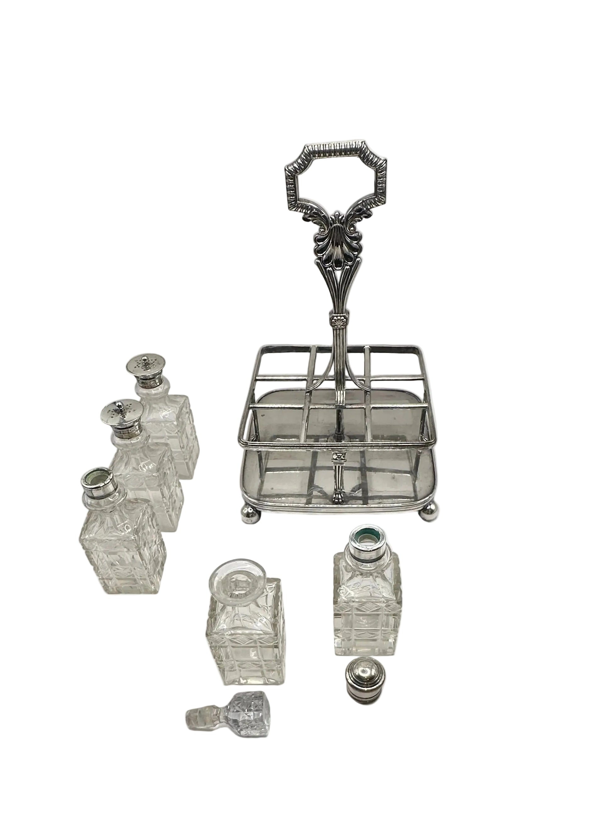 Antique cruet set, empty silver caddy beside its cut-glass bottles and stoppers