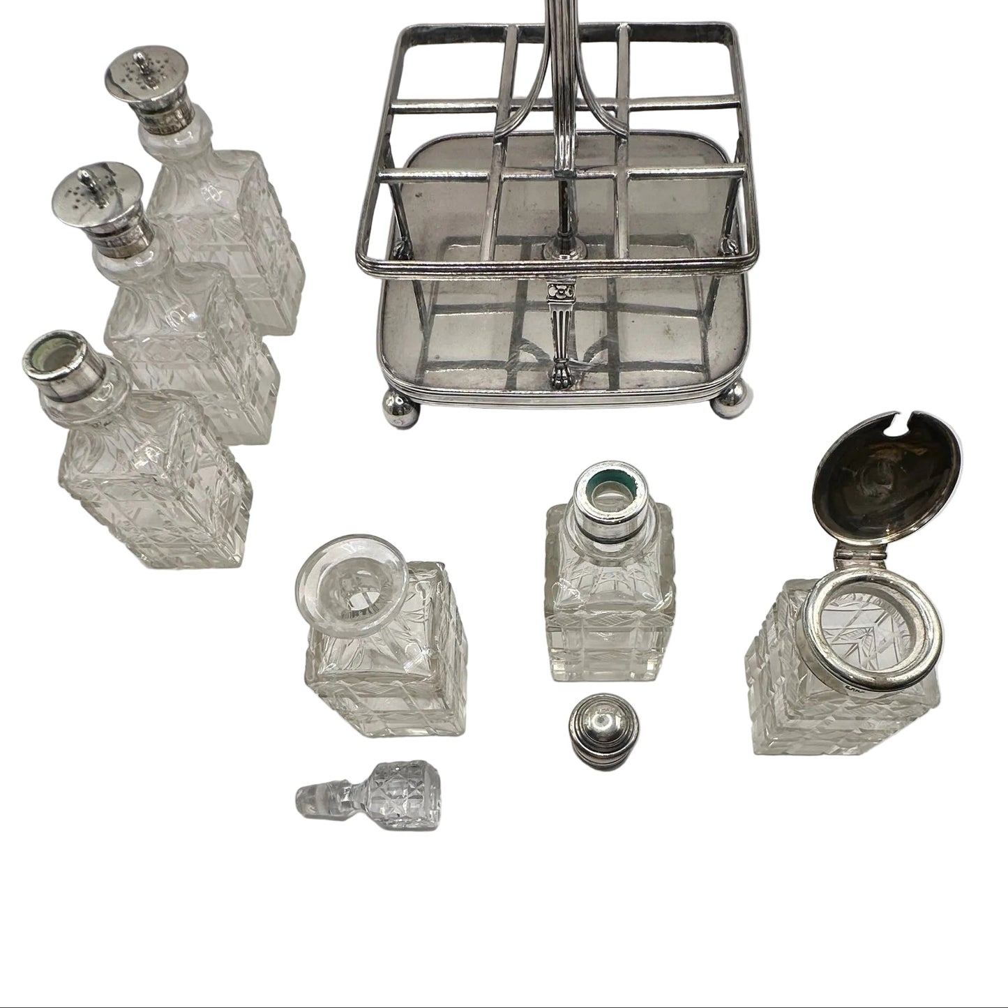 Antique cruet set disassembled, silver caddy with cut-glass bottles and stoppers laid out