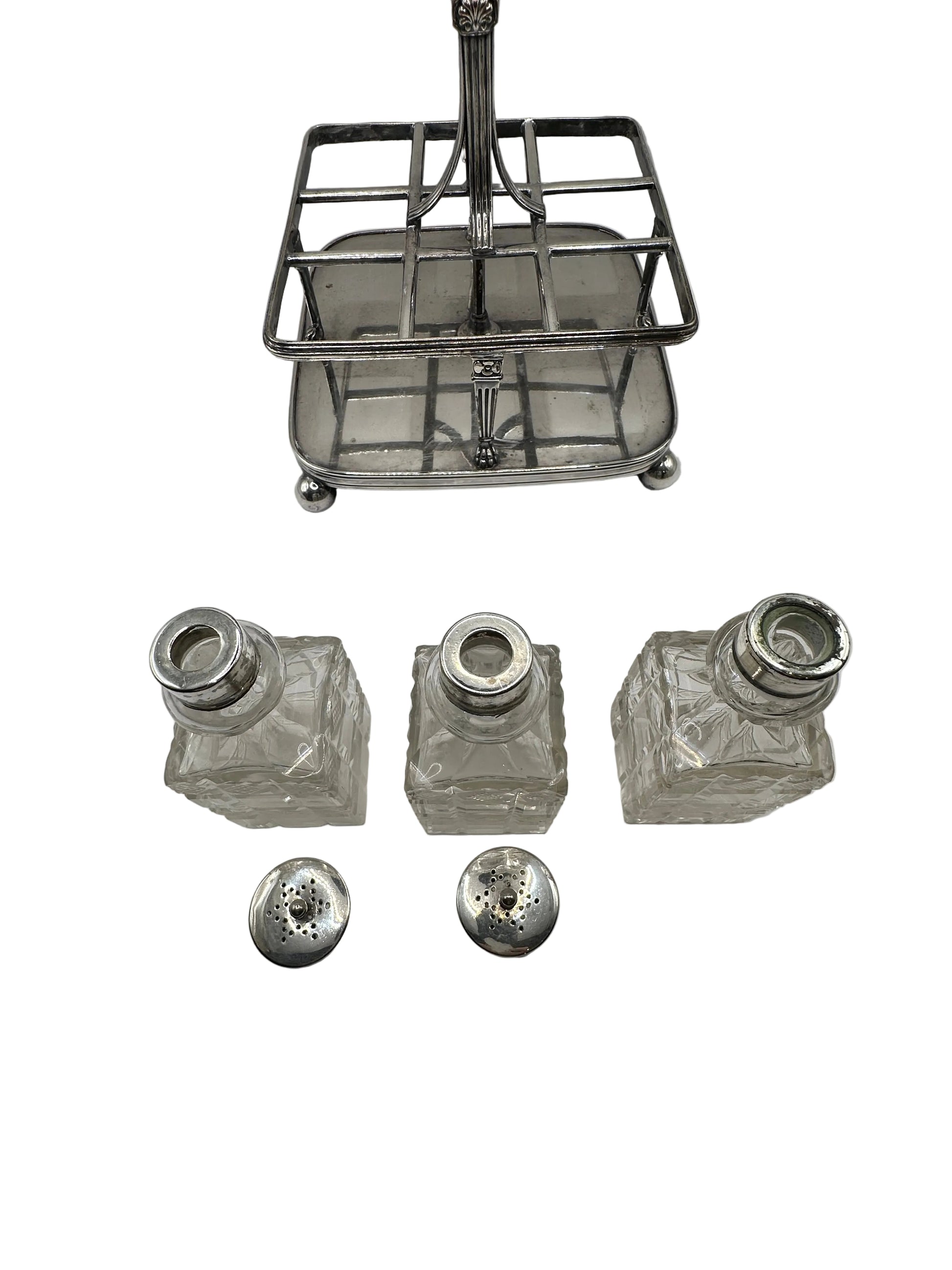Antique cruet set, silver caddy with three cut-glass bottles and two pierced shaker tops