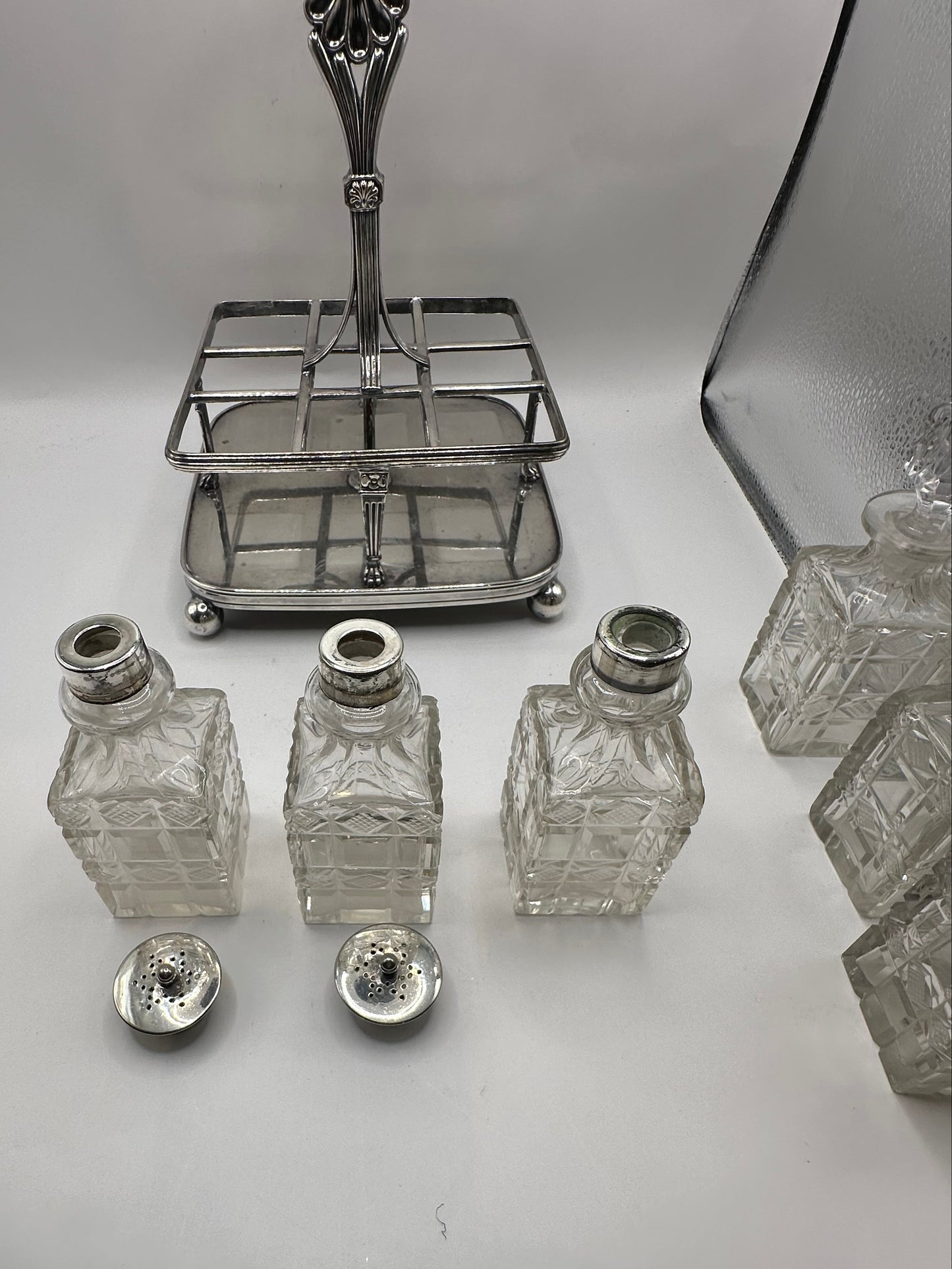 Antique cruet set, silver caddy with cut-glass bottles and pierced shaker lids displayed in front