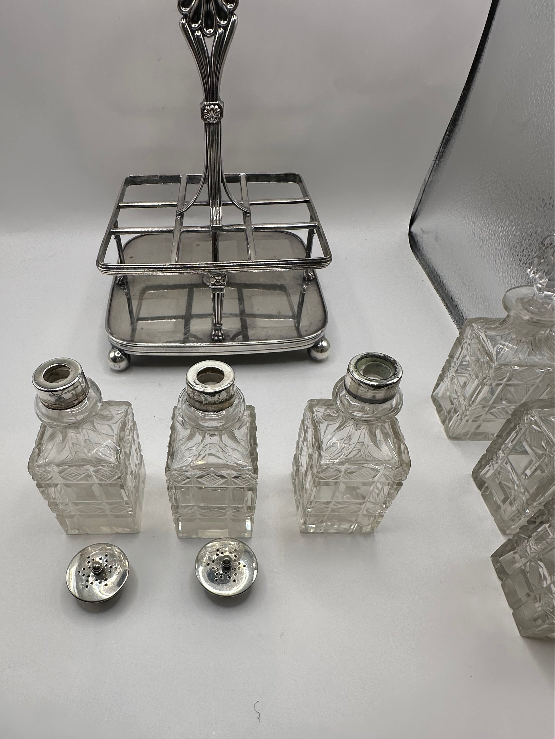 Antique cruet set, silver caddy with cut-glass bottles and pierced shaker lids displayed in front