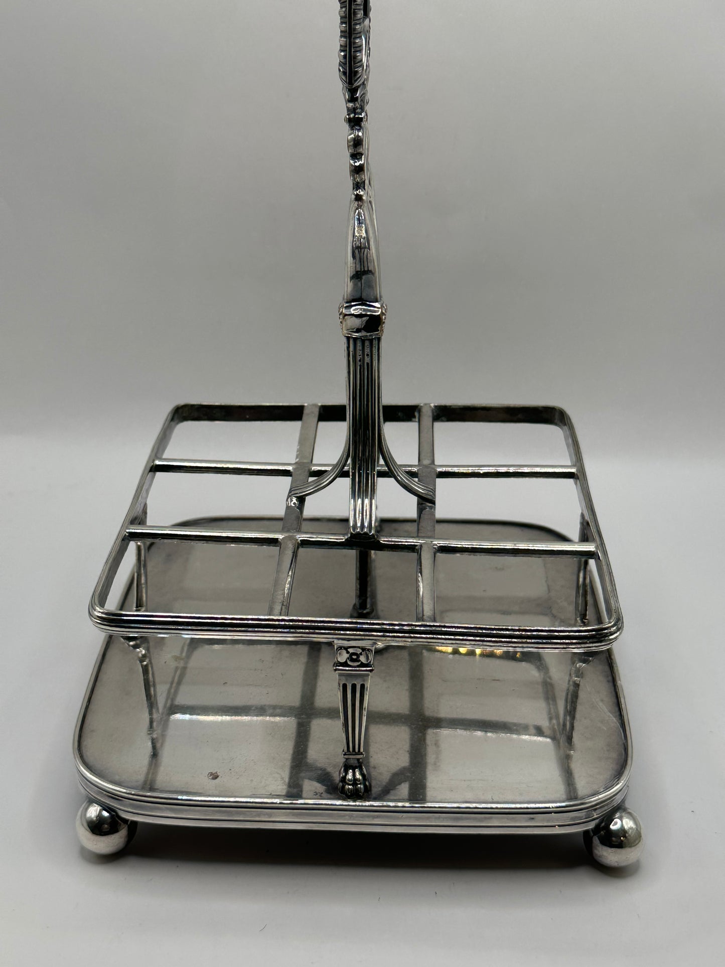 Close-up of the antique cruet set's silver caddy frame, base and ball feet