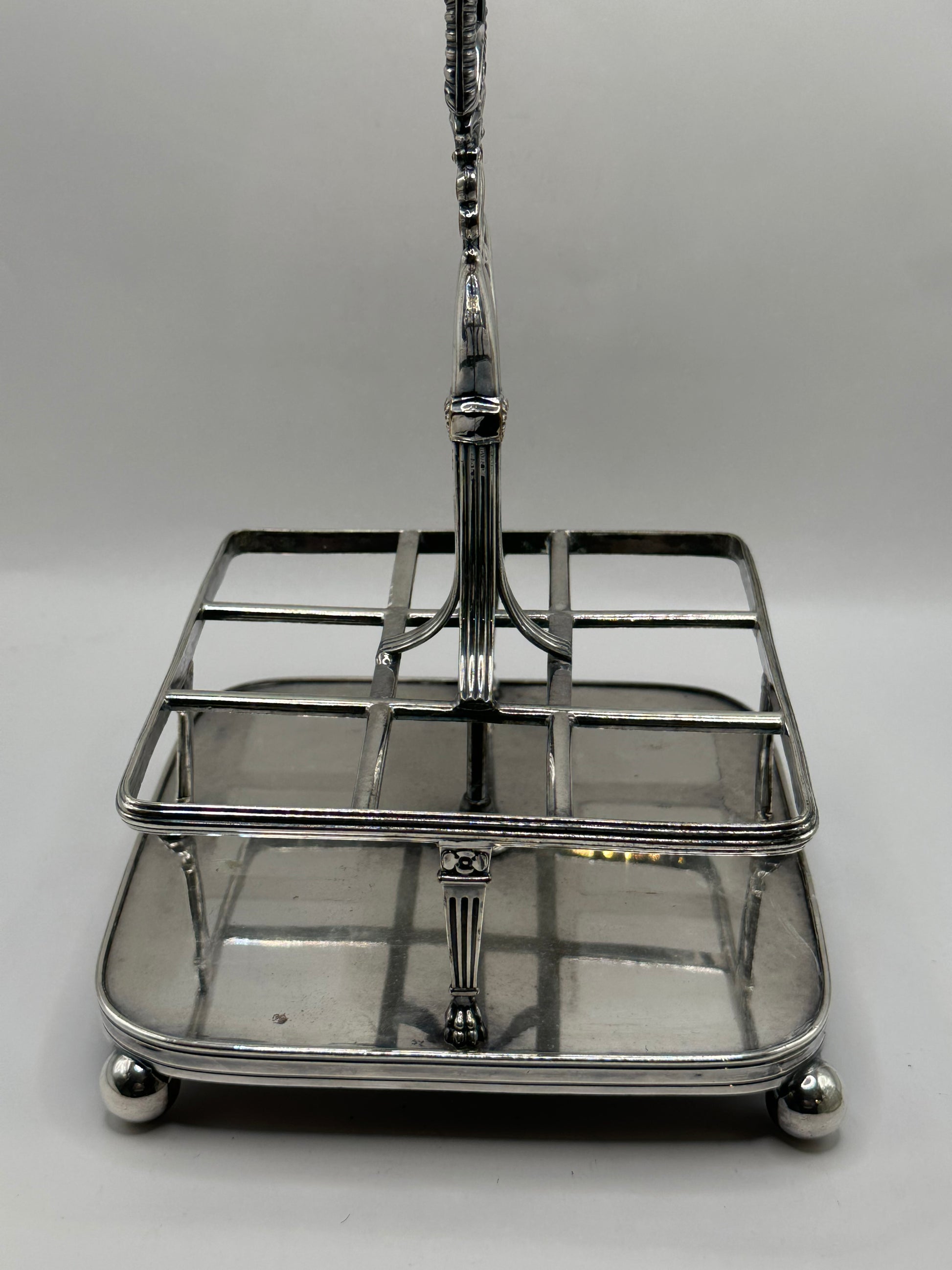 Close-up of the antique cruet set's silver caddy frame, base and ball feet