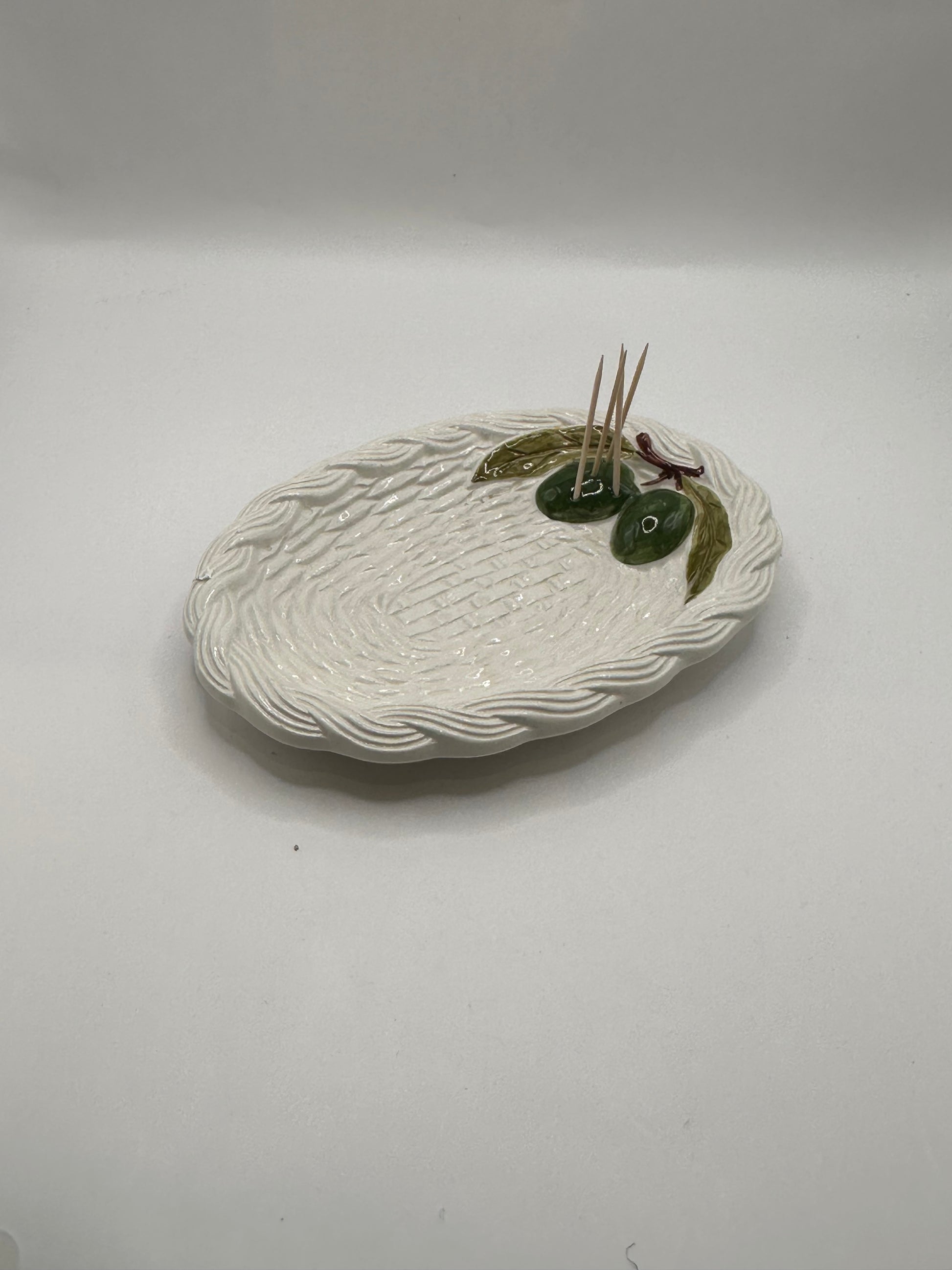 Italian ceramic olive dish, angled view with toothpicks tucked beside the olive cluster