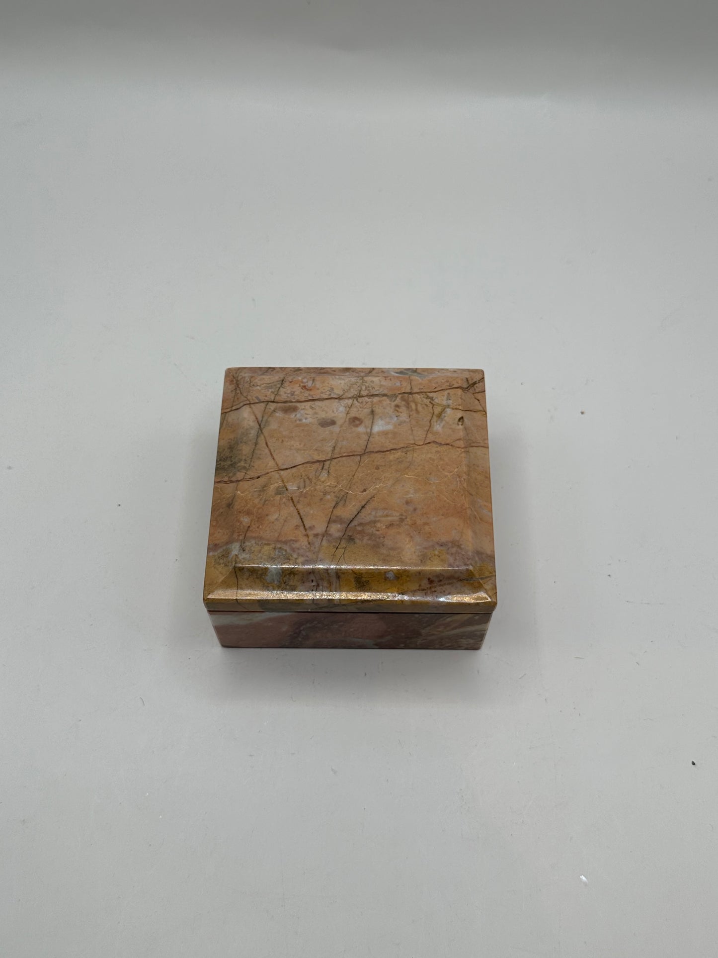 Closed rose marble lidded box, top-down view of polished grain