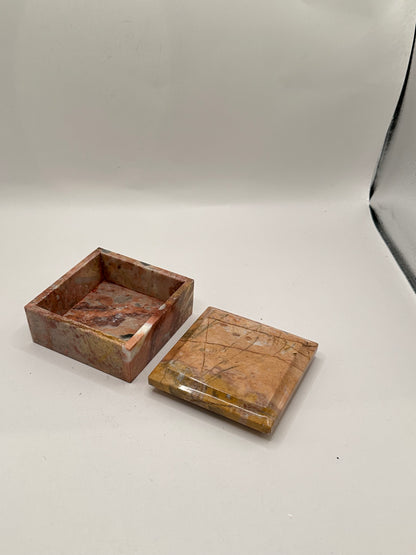 Open rose marble box with lid set beside the base