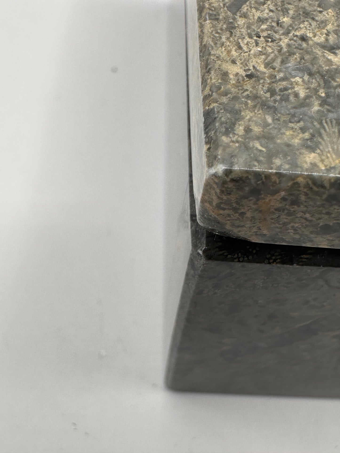 Close-up of the beveled corner and edge detail of the gray stone box