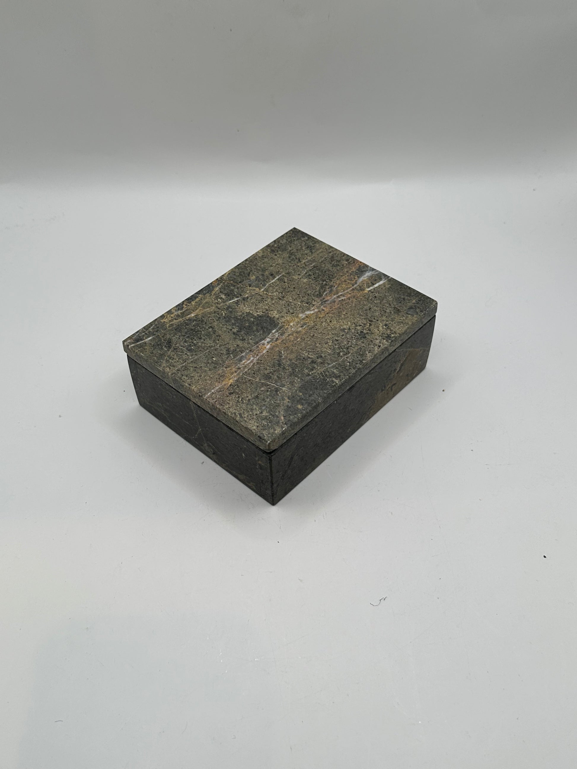 Closed gray stone box, angled view showing white and rust veins