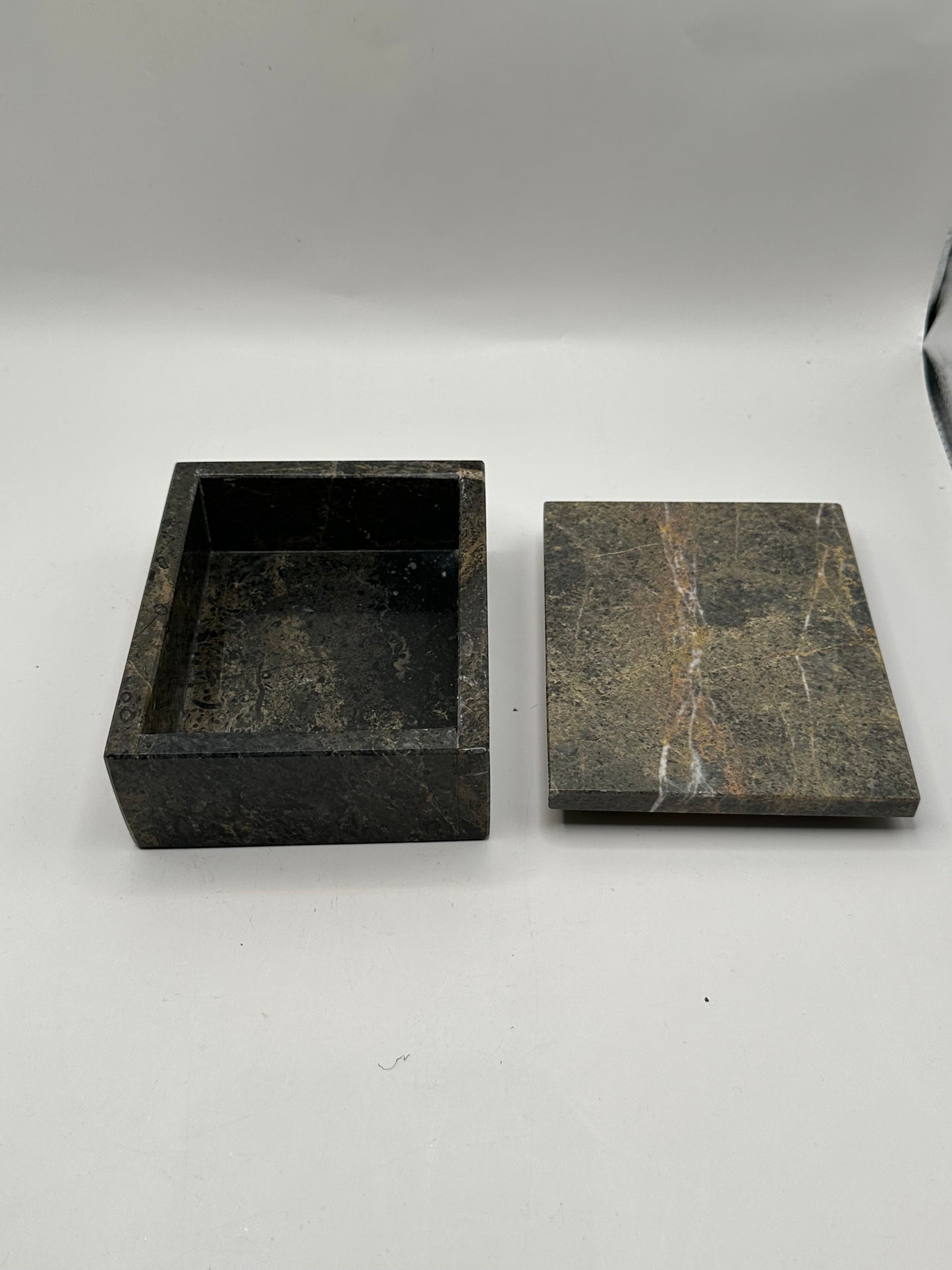 Open gray stone box with white-veined lid set beside the base