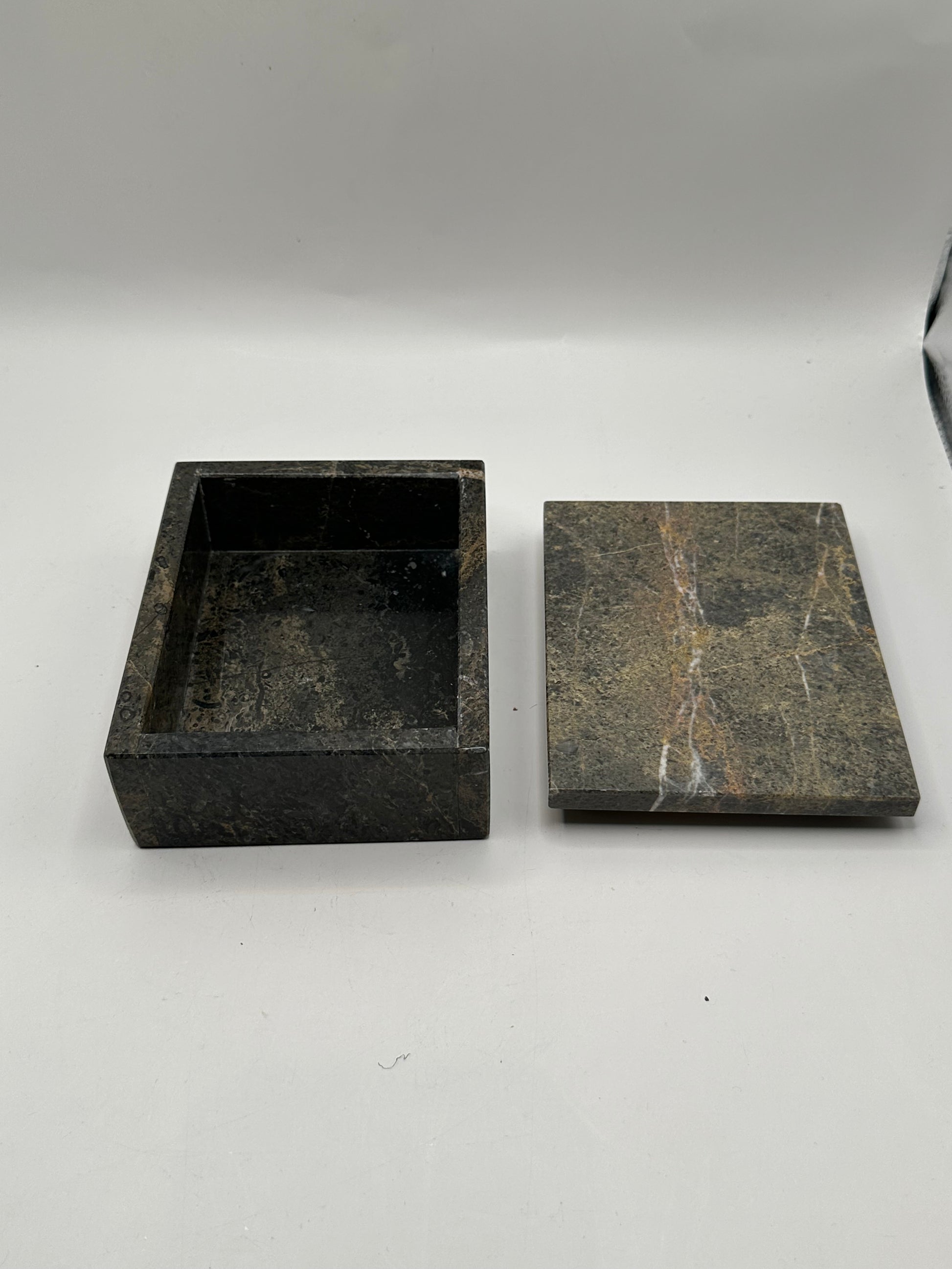 Open gray stone box with white-veined lid set beside the base