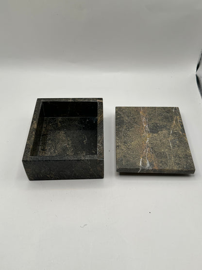 Open gray stone box with white-veined lid set beside the base