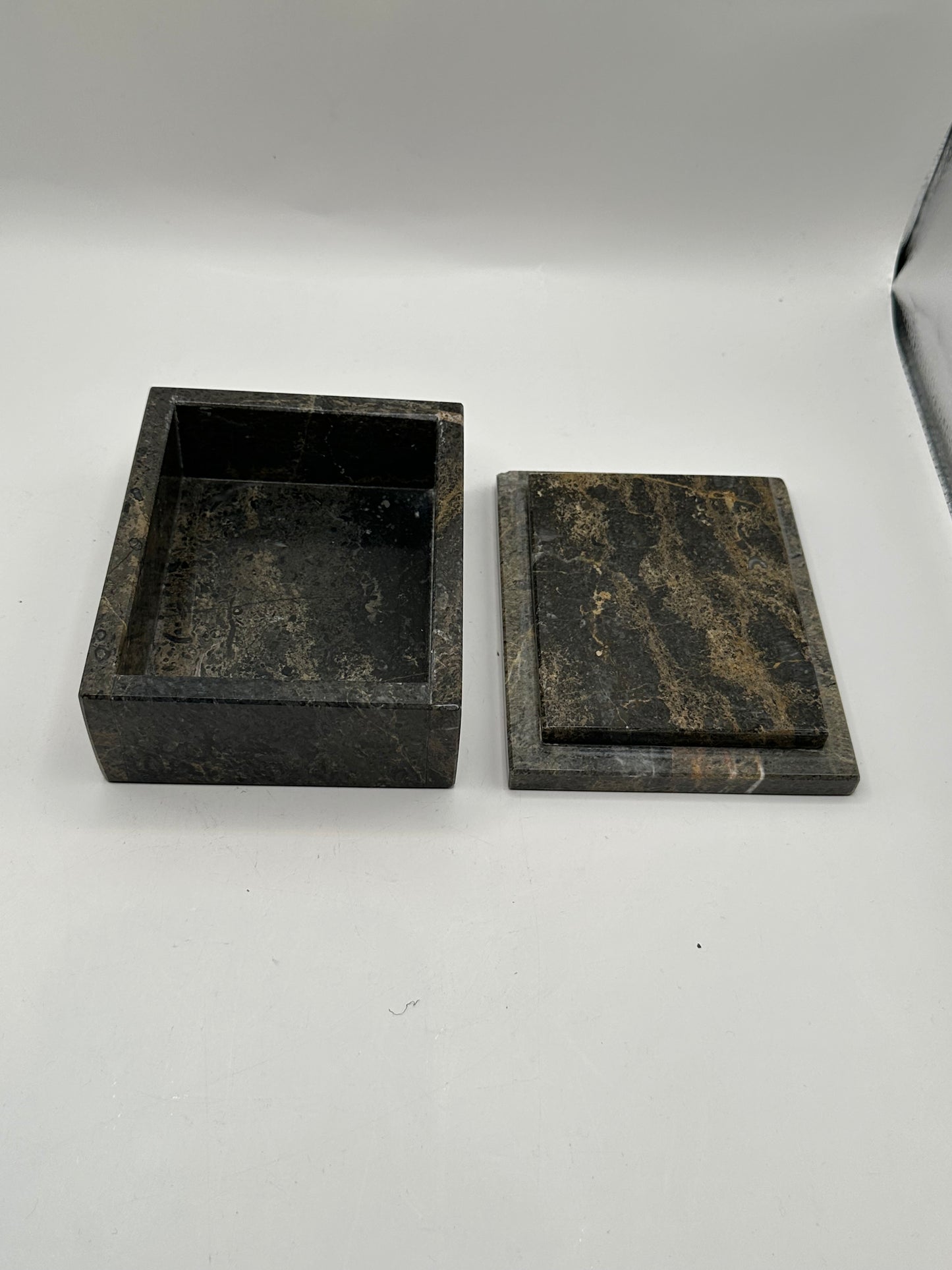 Open gray stone box with lid aside, revealing dark interior