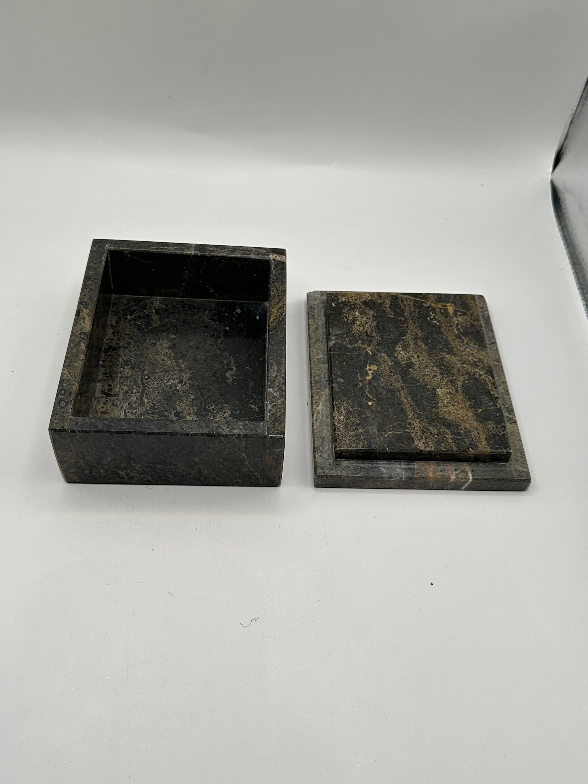 Open gray stone box with lid aside, revealing dark interior