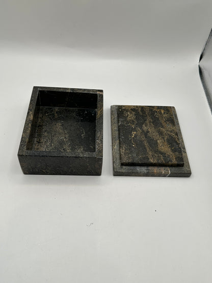 Open gray stone box with lid aside, revealing dark interior