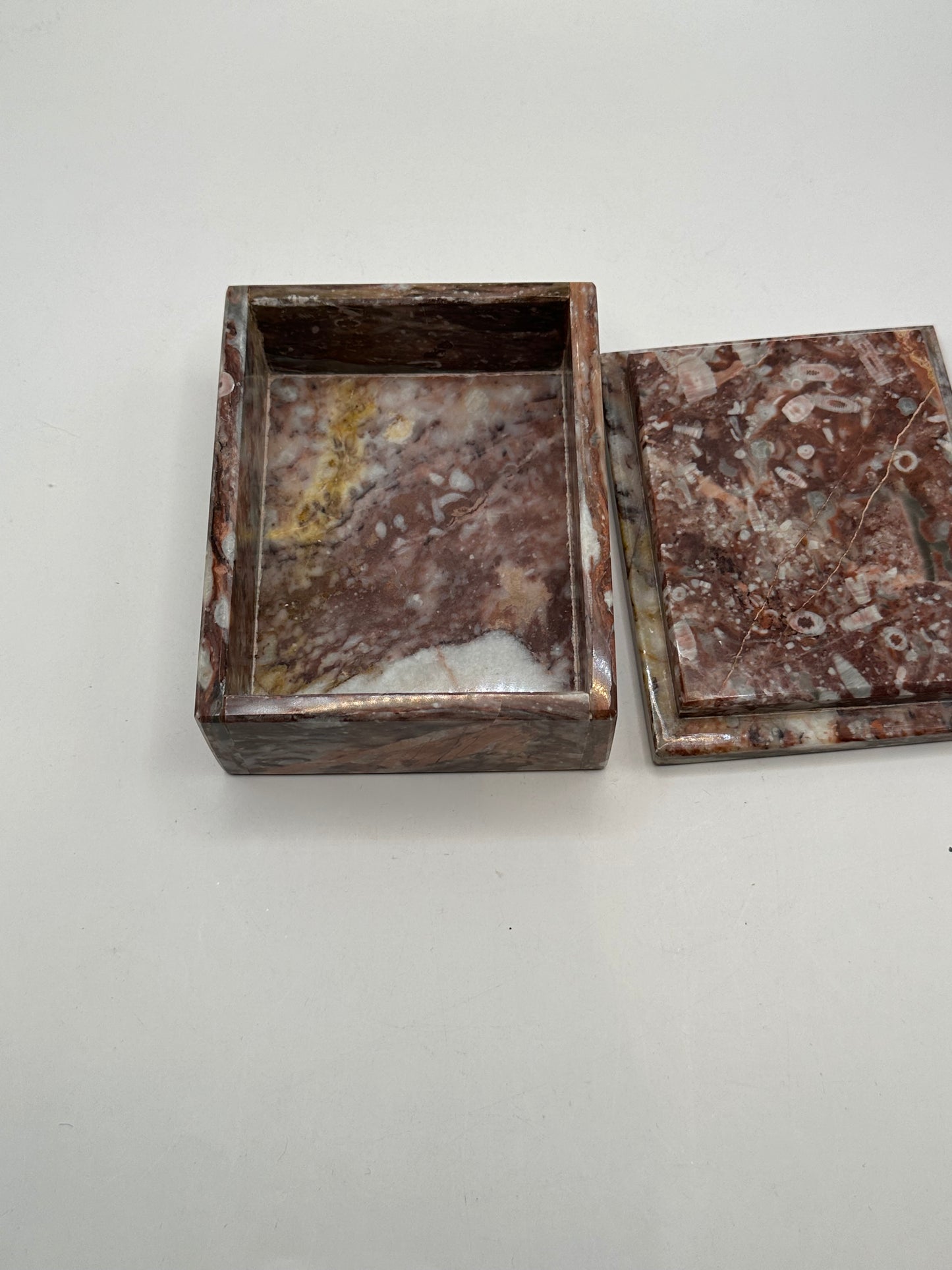 Open rust marble box showing fossil-flecked lid beside the base
