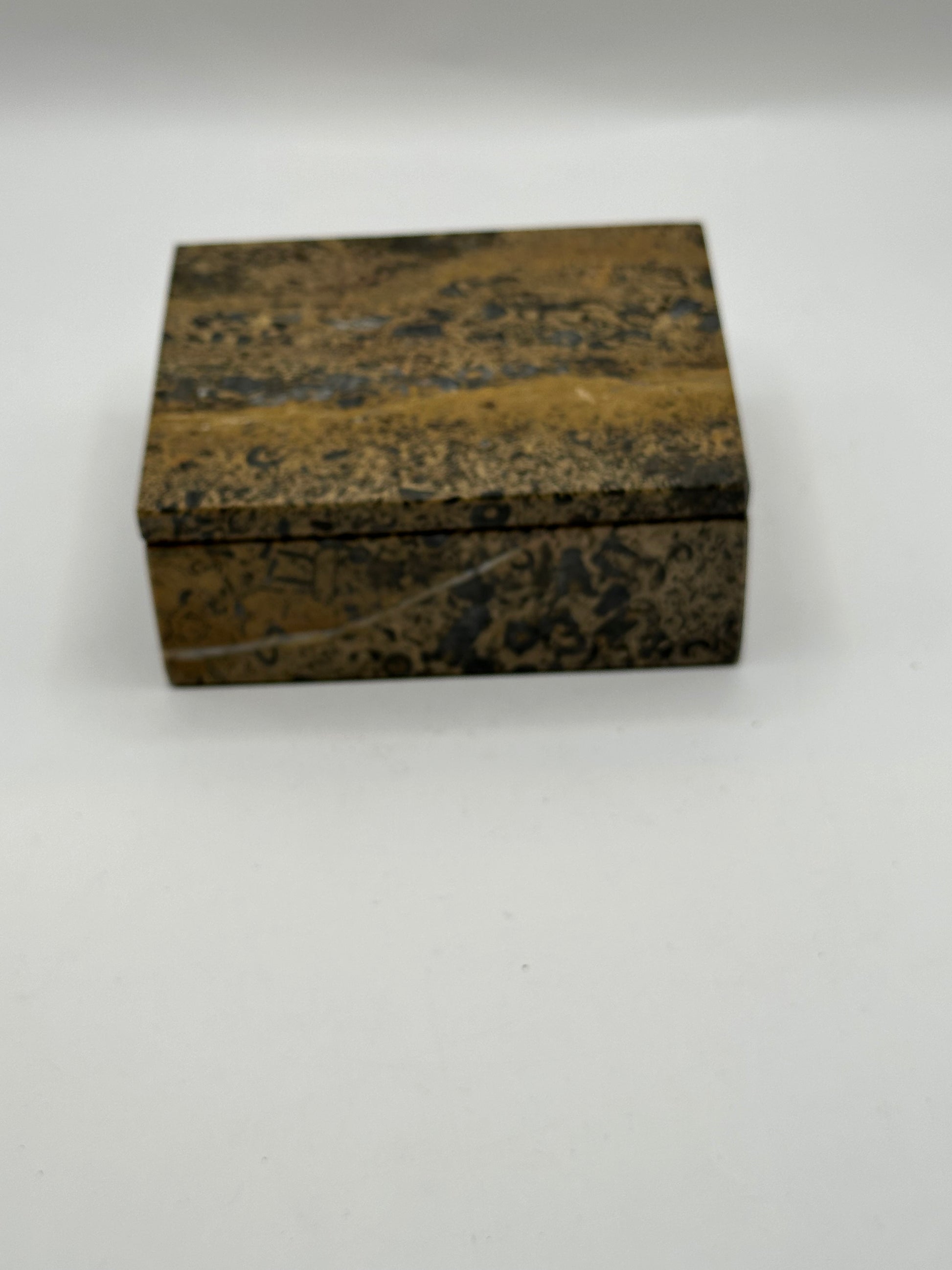Closed brown stone lidded box, angled view highlighting black and tan veining