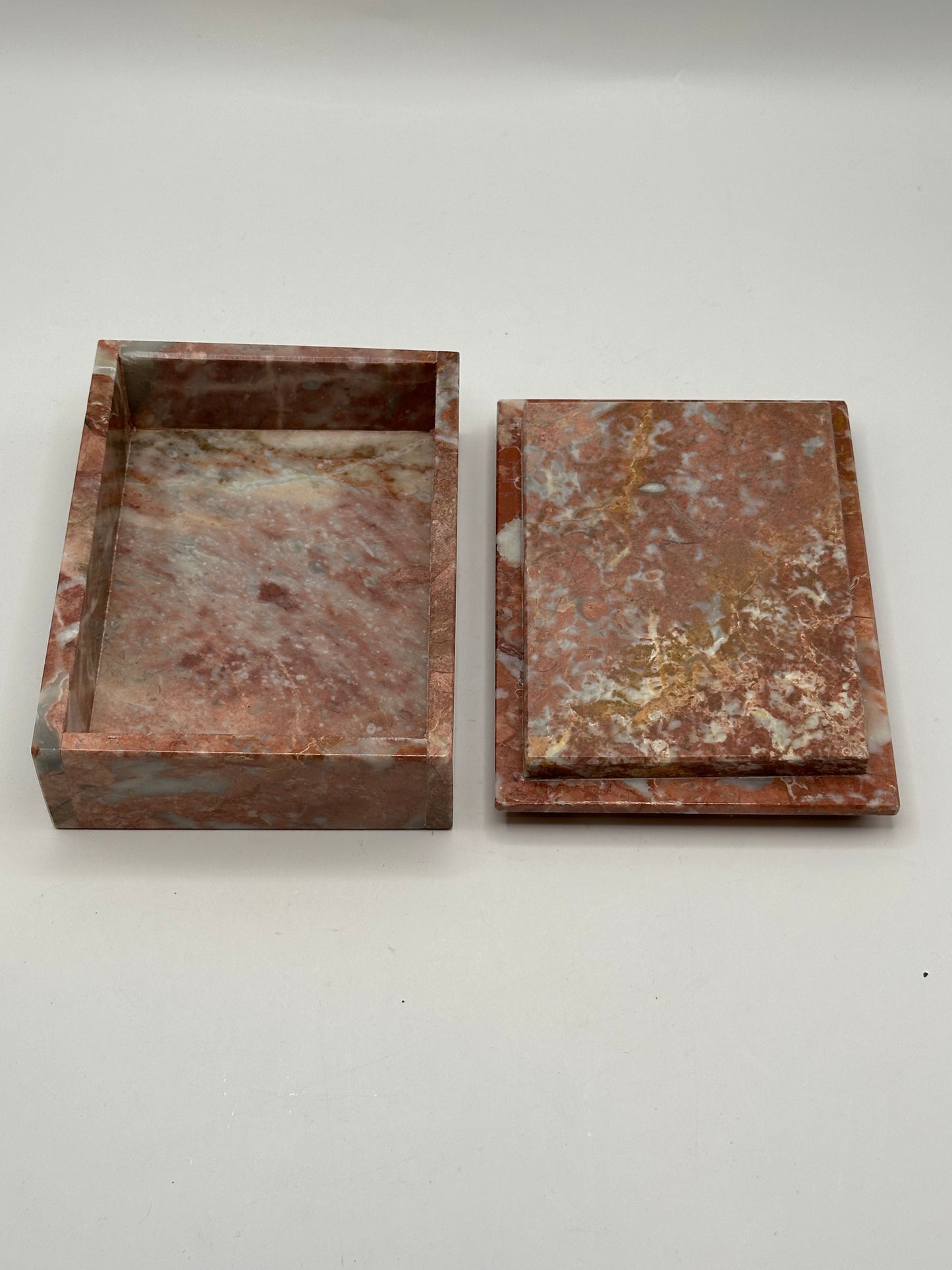 Open rust marble box with lid set beside the base