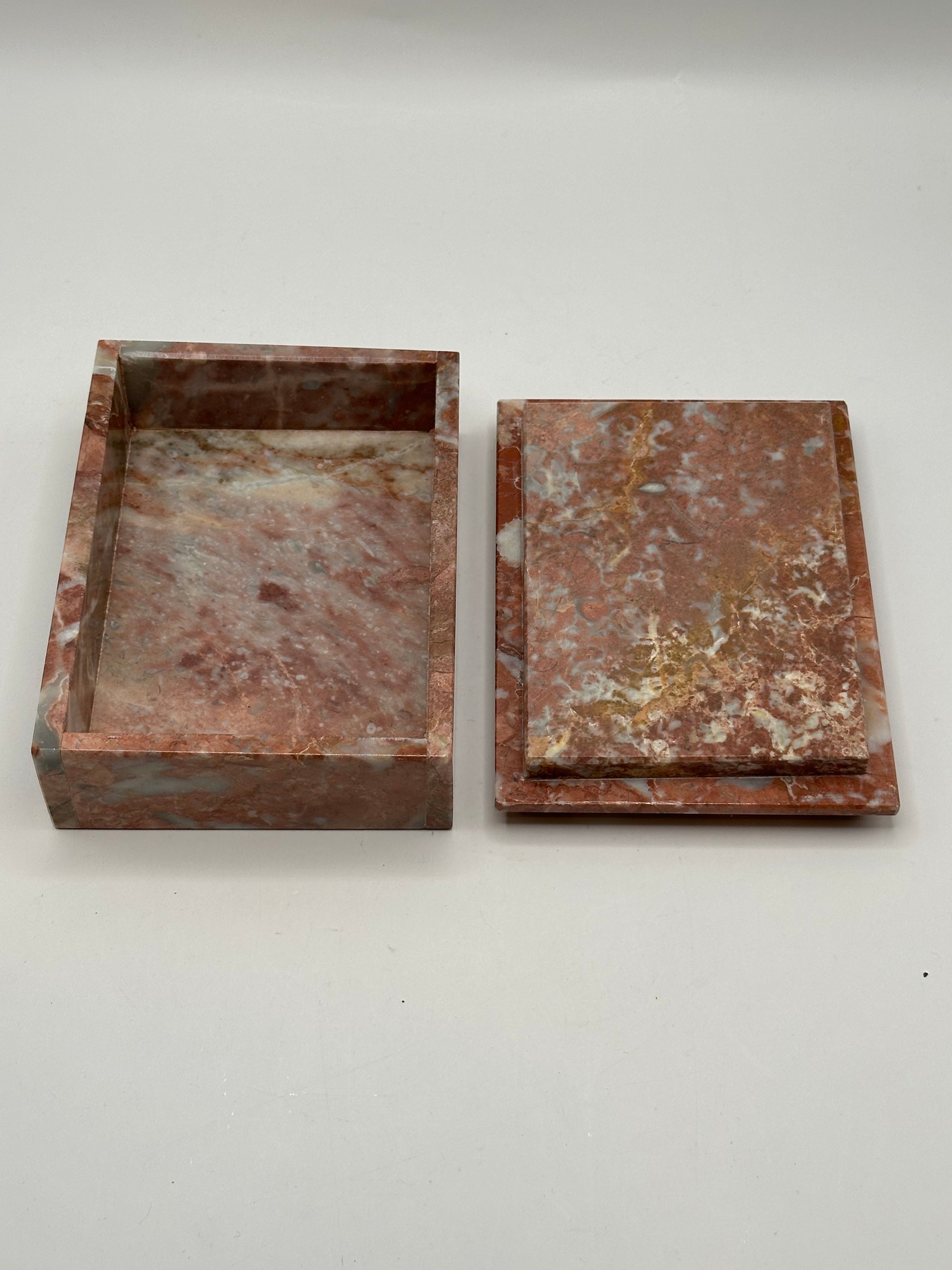 Open rust marble box with lid set beside the base