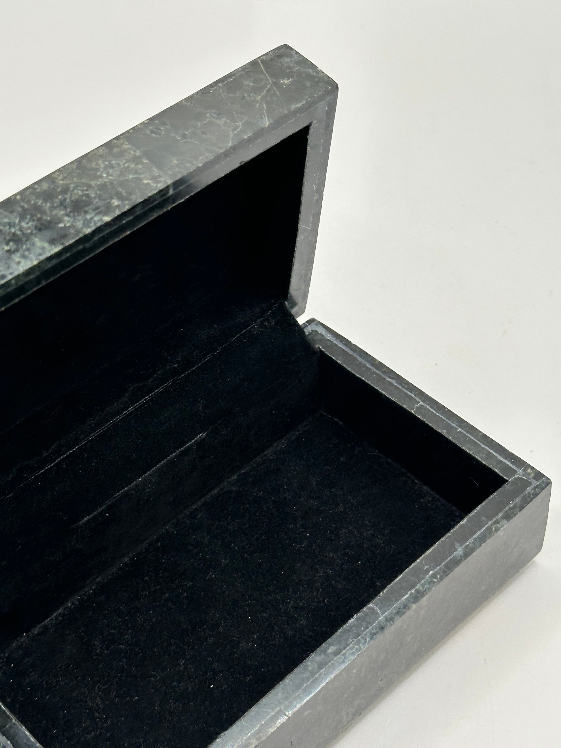 Open black tessellated stone box revealing black felt-lined interior