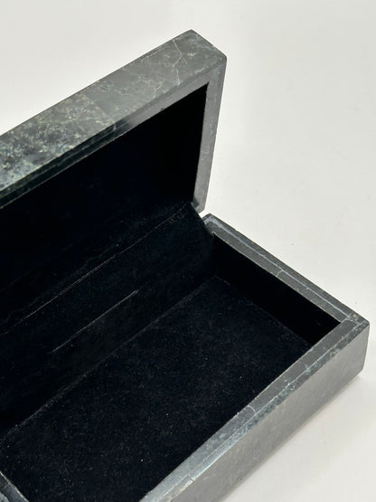 Open black tessellated stone box revealing black felt-lined interior