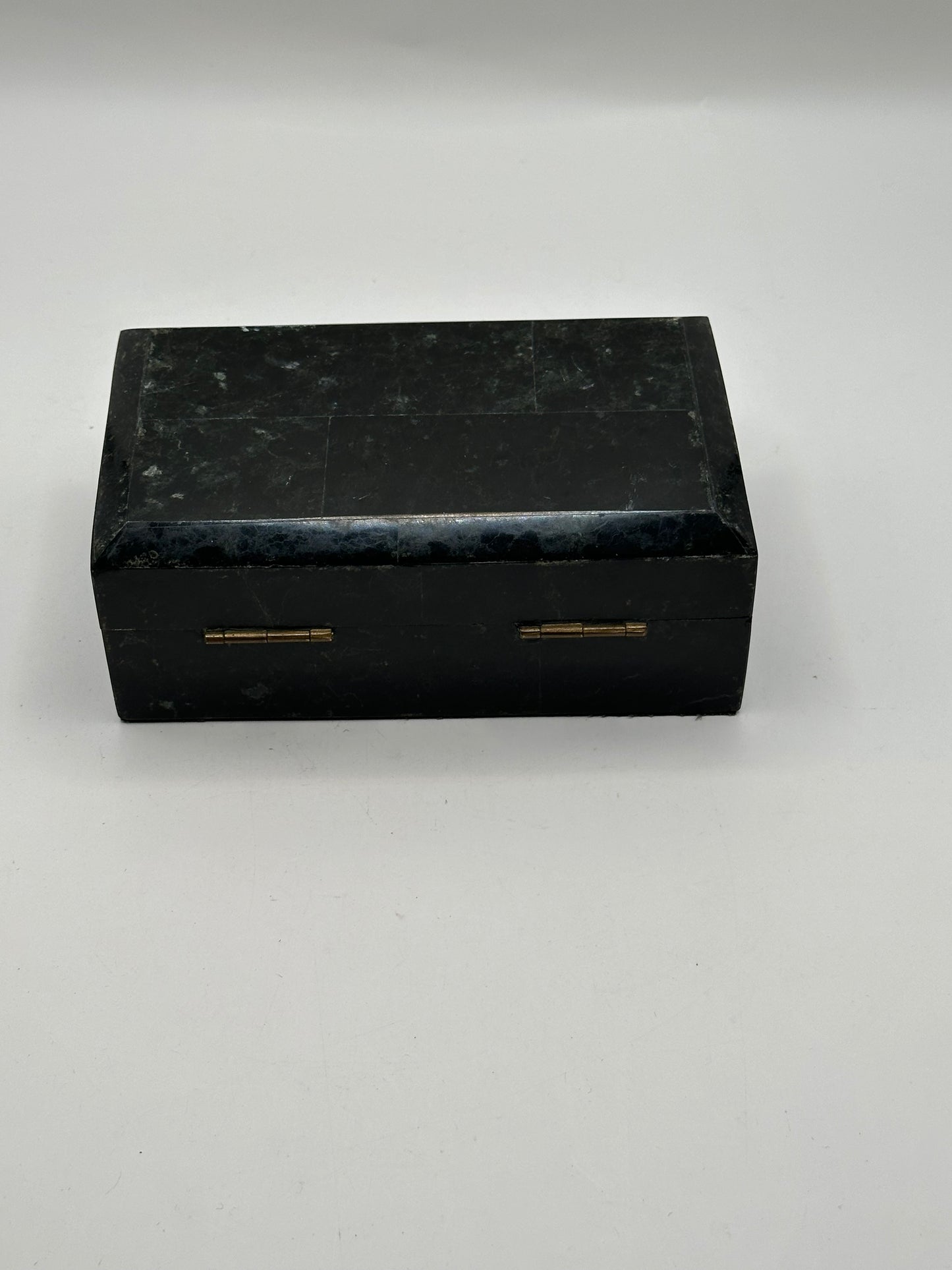 Closed black tessellated hinged box with brass hinges, front view
