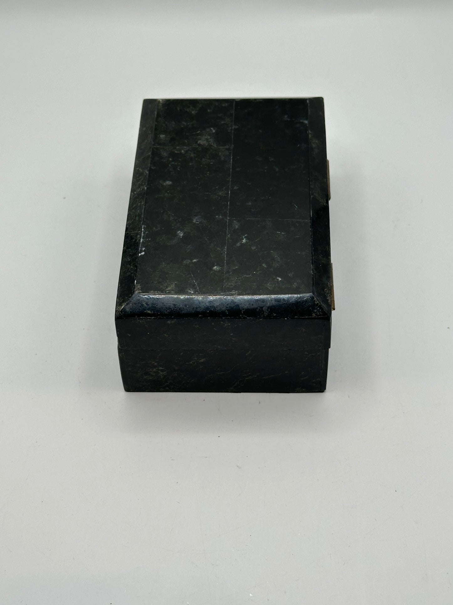 Rear of the black tessellated box showing two brass hinges