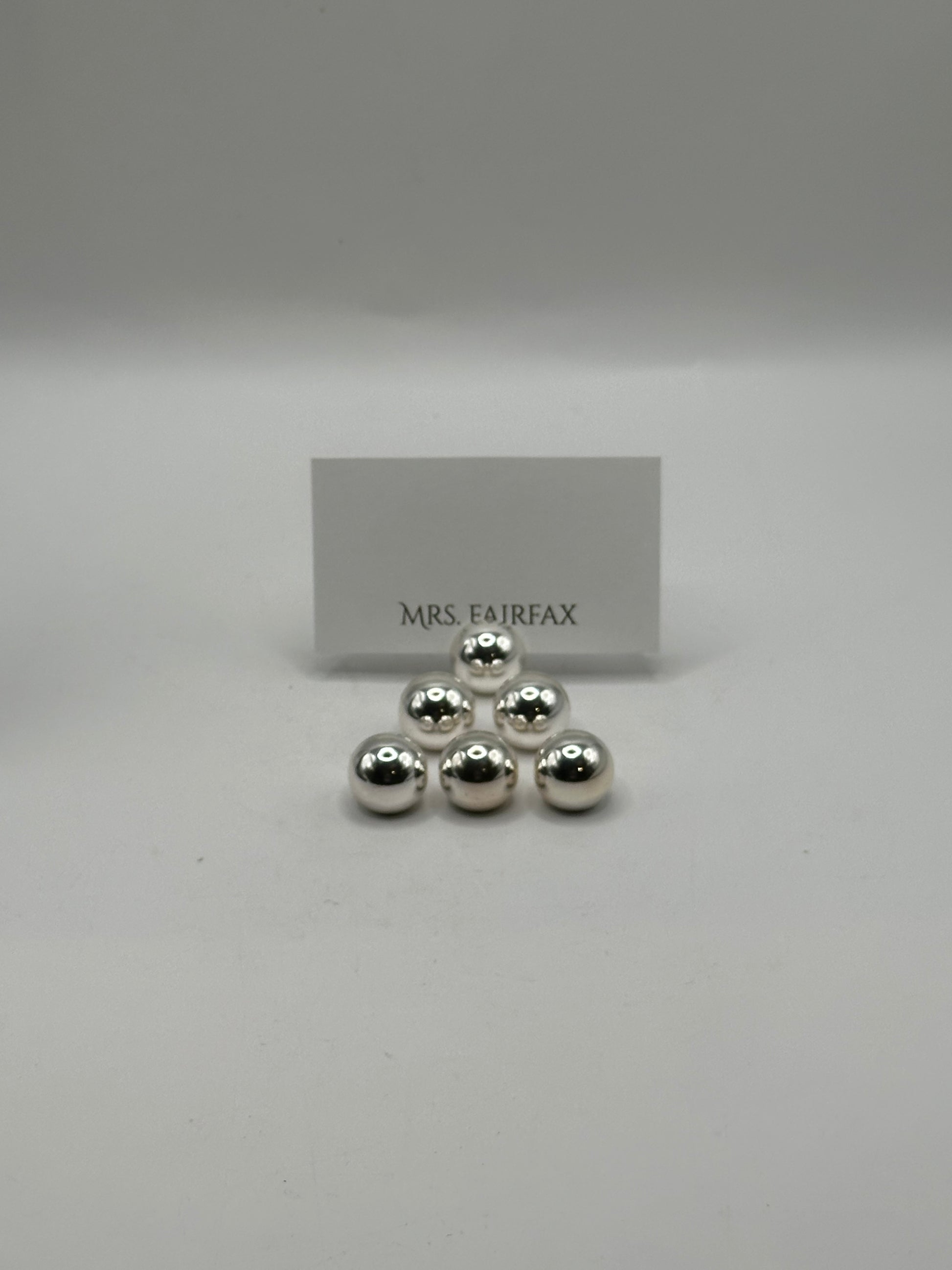 MCM stainless steel spherical place card holders, six spheres stacked with a place card behind