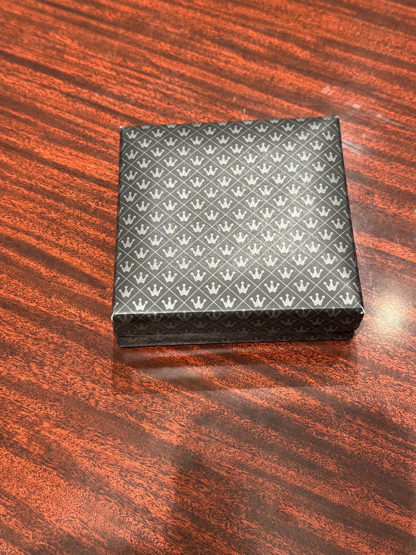 MCM stainless steel place card holders in a closed crown-patterned gift box on a wood surface