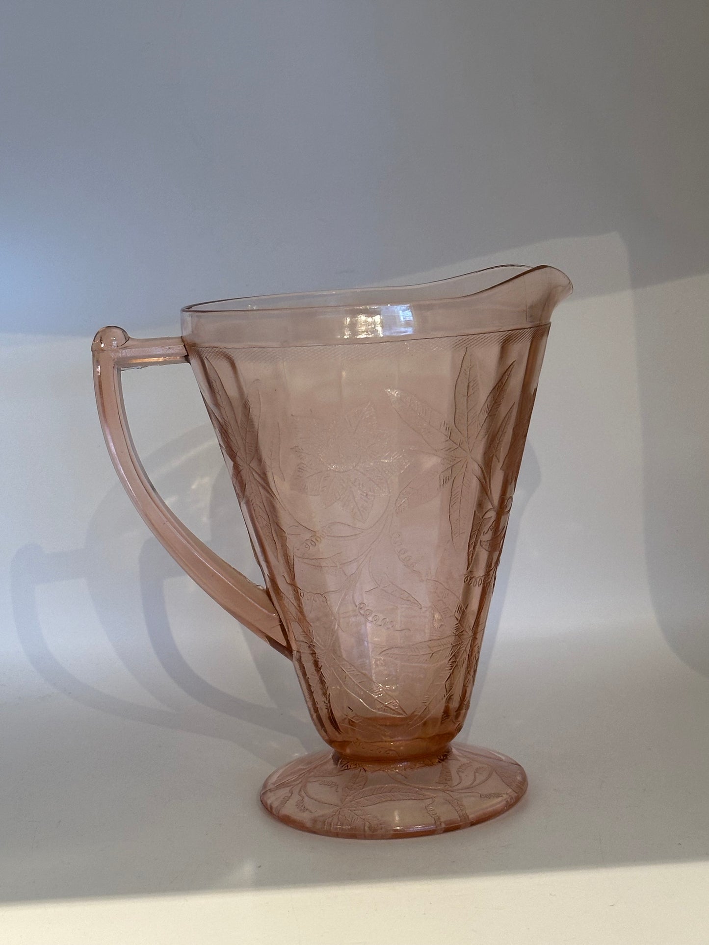 Pink Depression glass pitcher, angled view showing handle and etched floral design