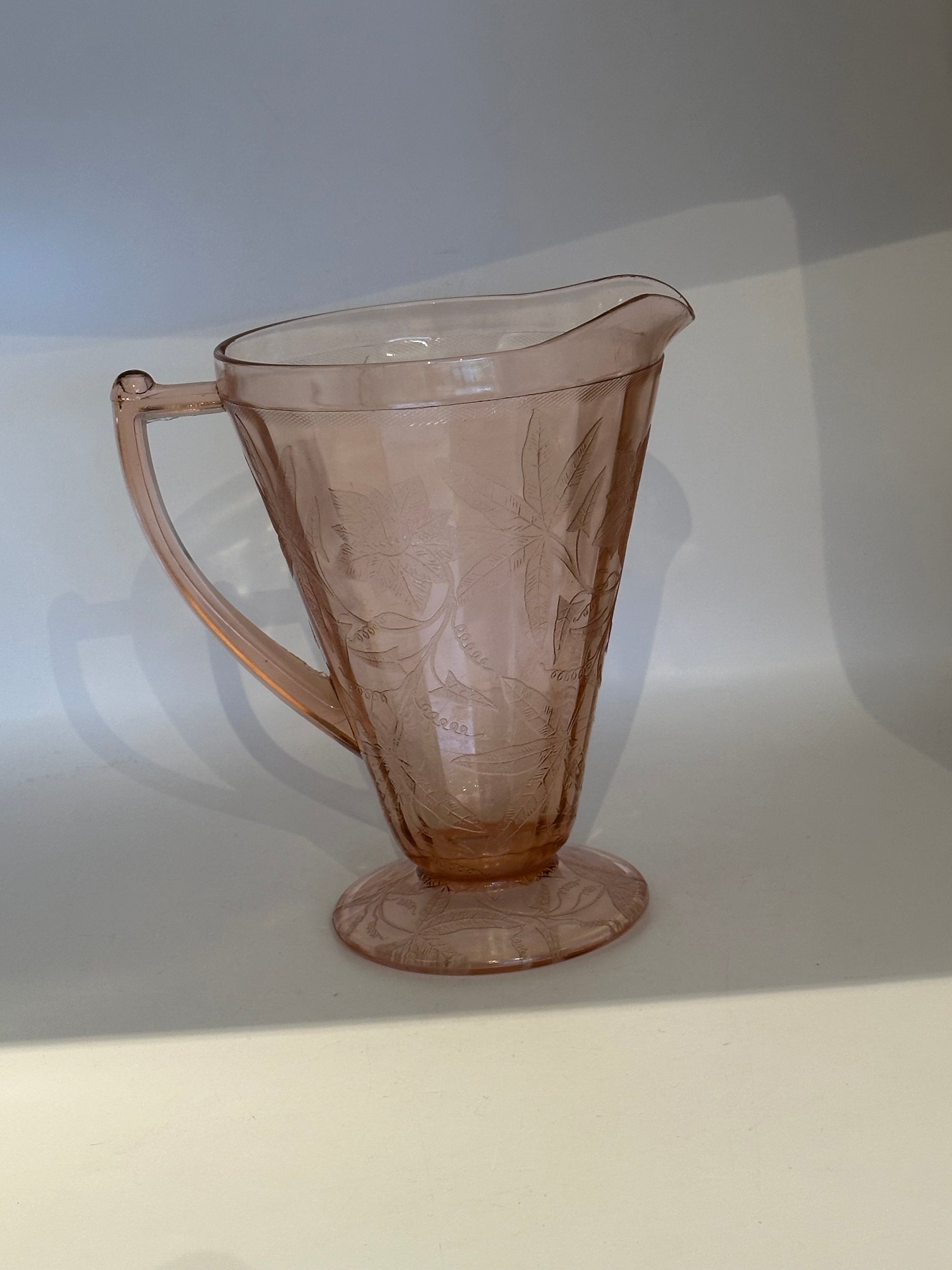 Pink Depression glass pitcher with curved handle and pinched spout, three-quarter view