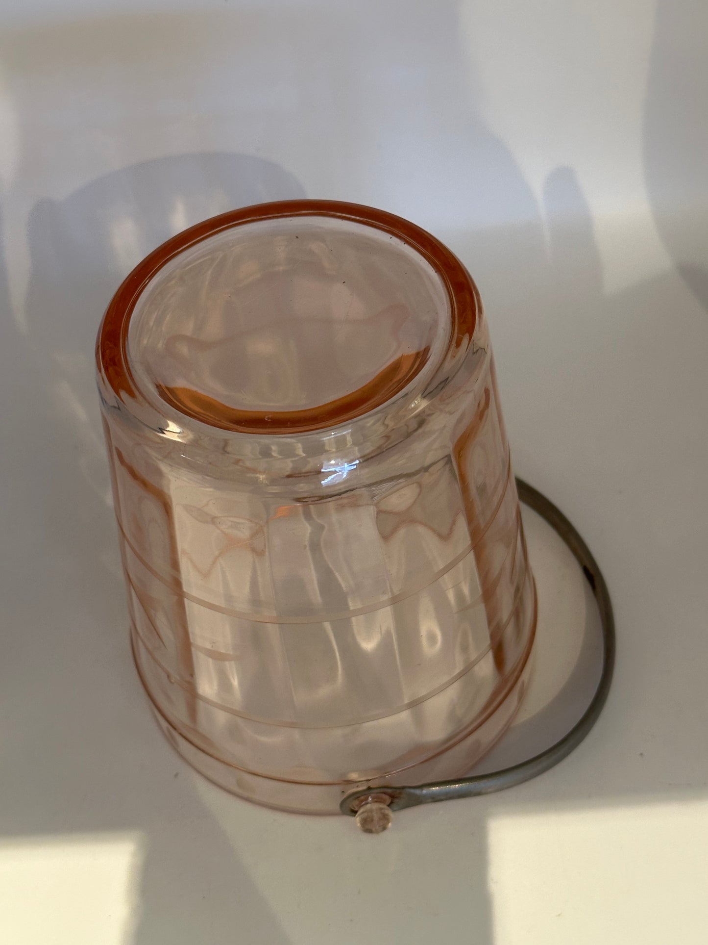Pink glass ice bucket turned to show base and etched panels