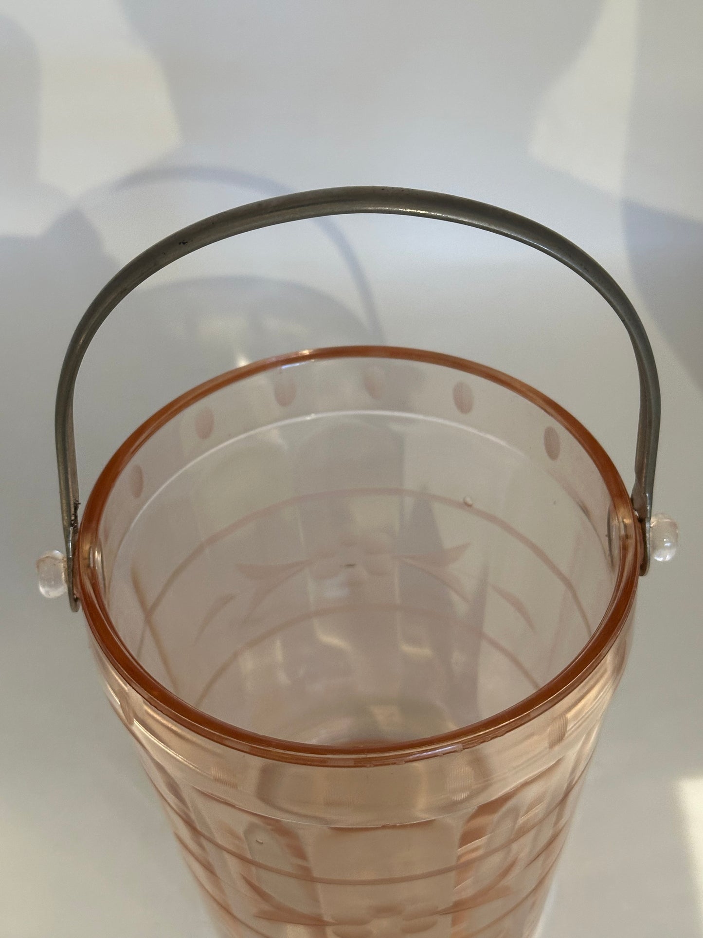 Top view into the pink glass ice bucket showing etched bands and metal handle