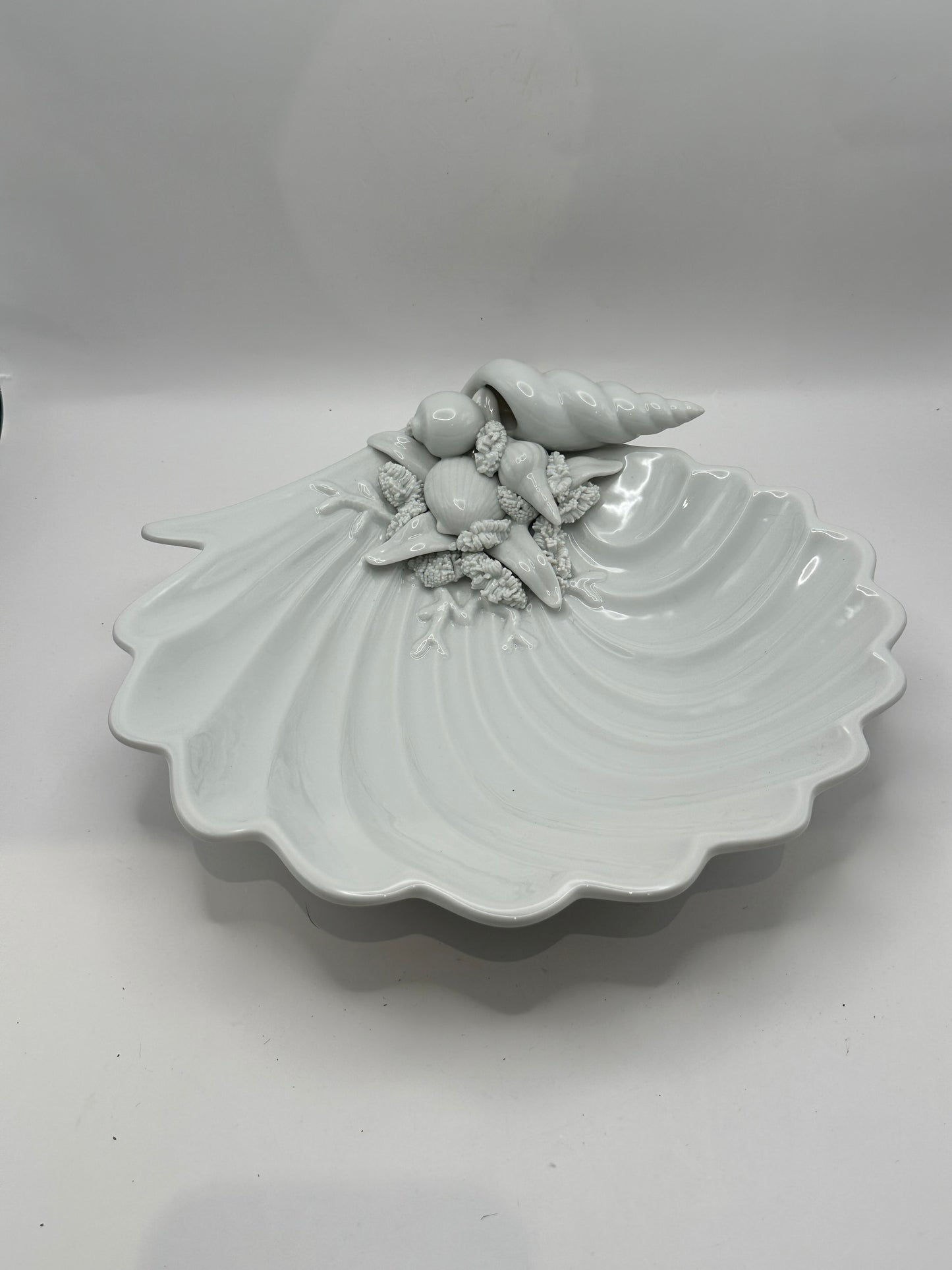 White porcelain scallop shell dish with molded seashells and conch, three-quarter view