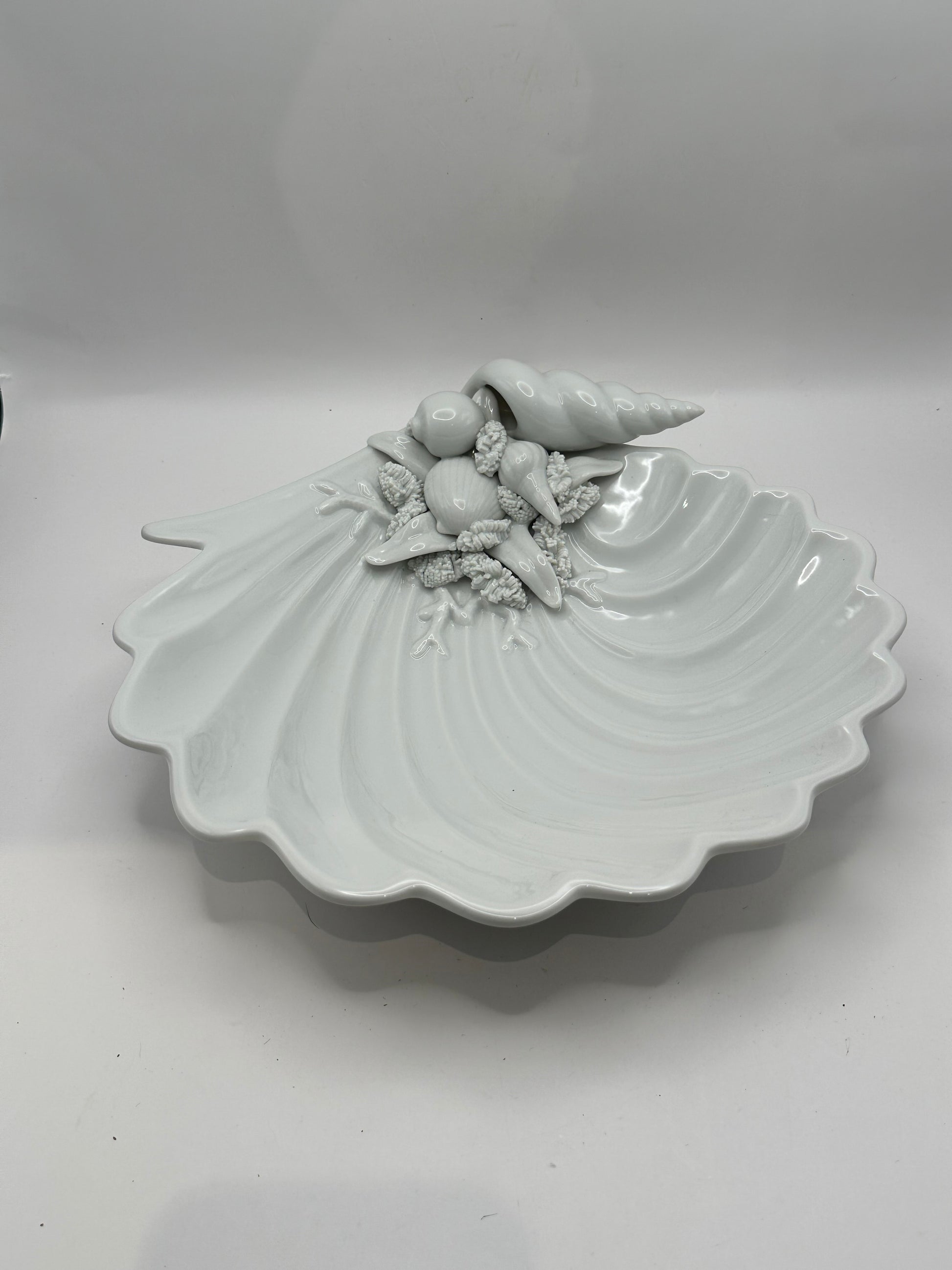 White porcelain scallop shell dish with molded seashells and conch, three-quarter view