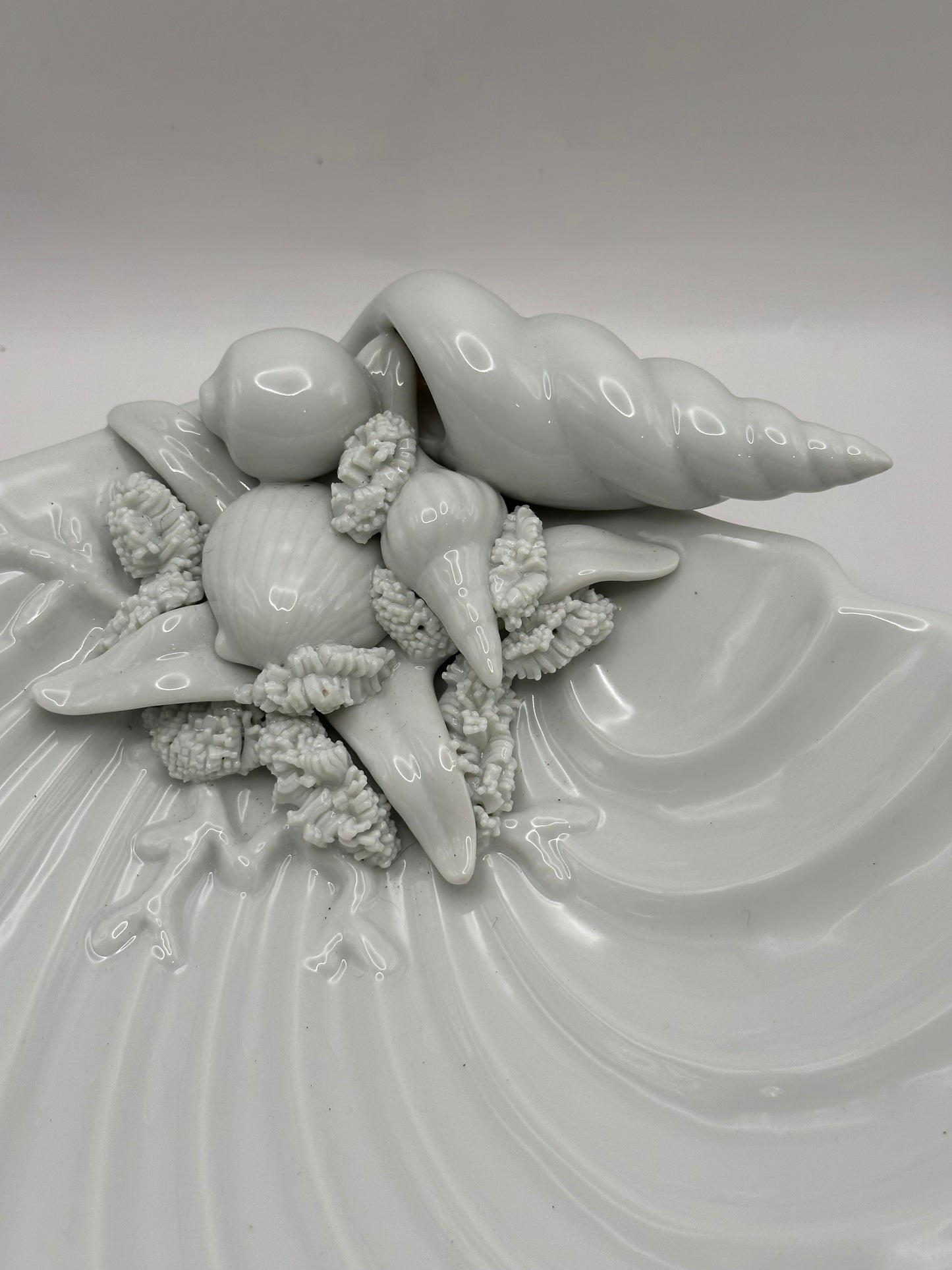 Close-up of the molded seashells, conch and starfish detail on the white porcelain shell dish