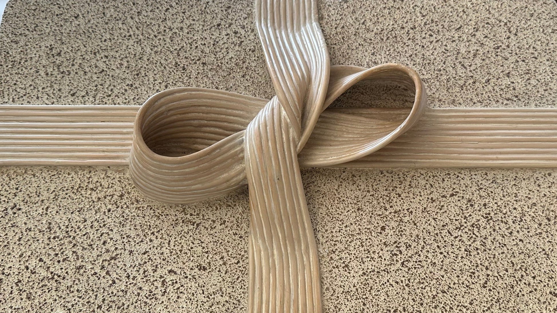 Close-up of the carved pencil-reed ribbon-and-bow detail on the box lid
