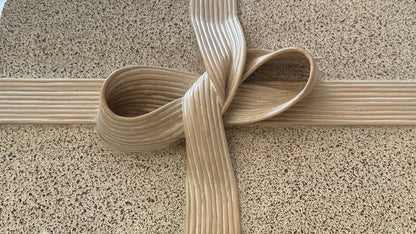 Close-up of the carved pencil-reed ribbon-and-bow detail on the box lid
