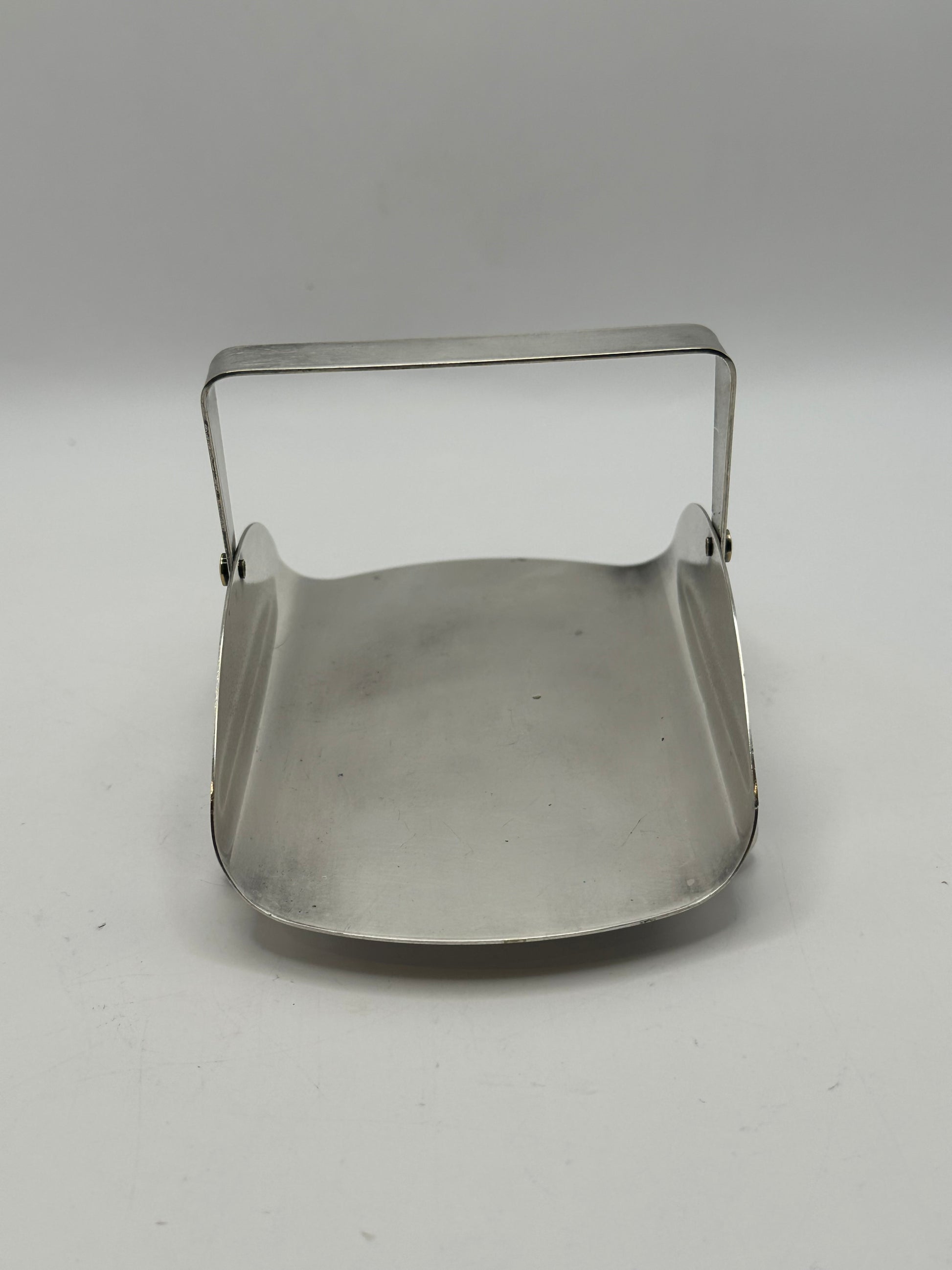 Silver-plate basket with its swing handle raised, showing the curved square dish