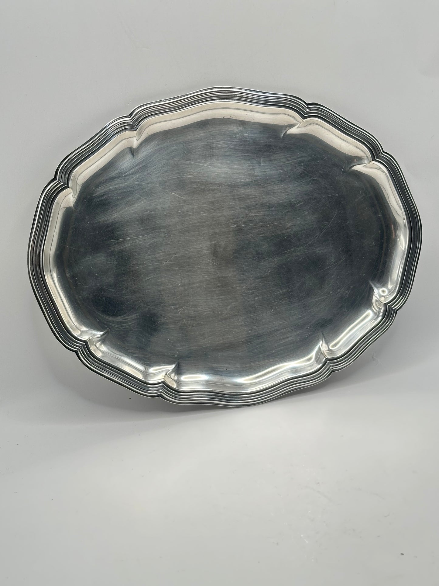 Top-down view of the oval silver-plate tray with its scalloped molded rim