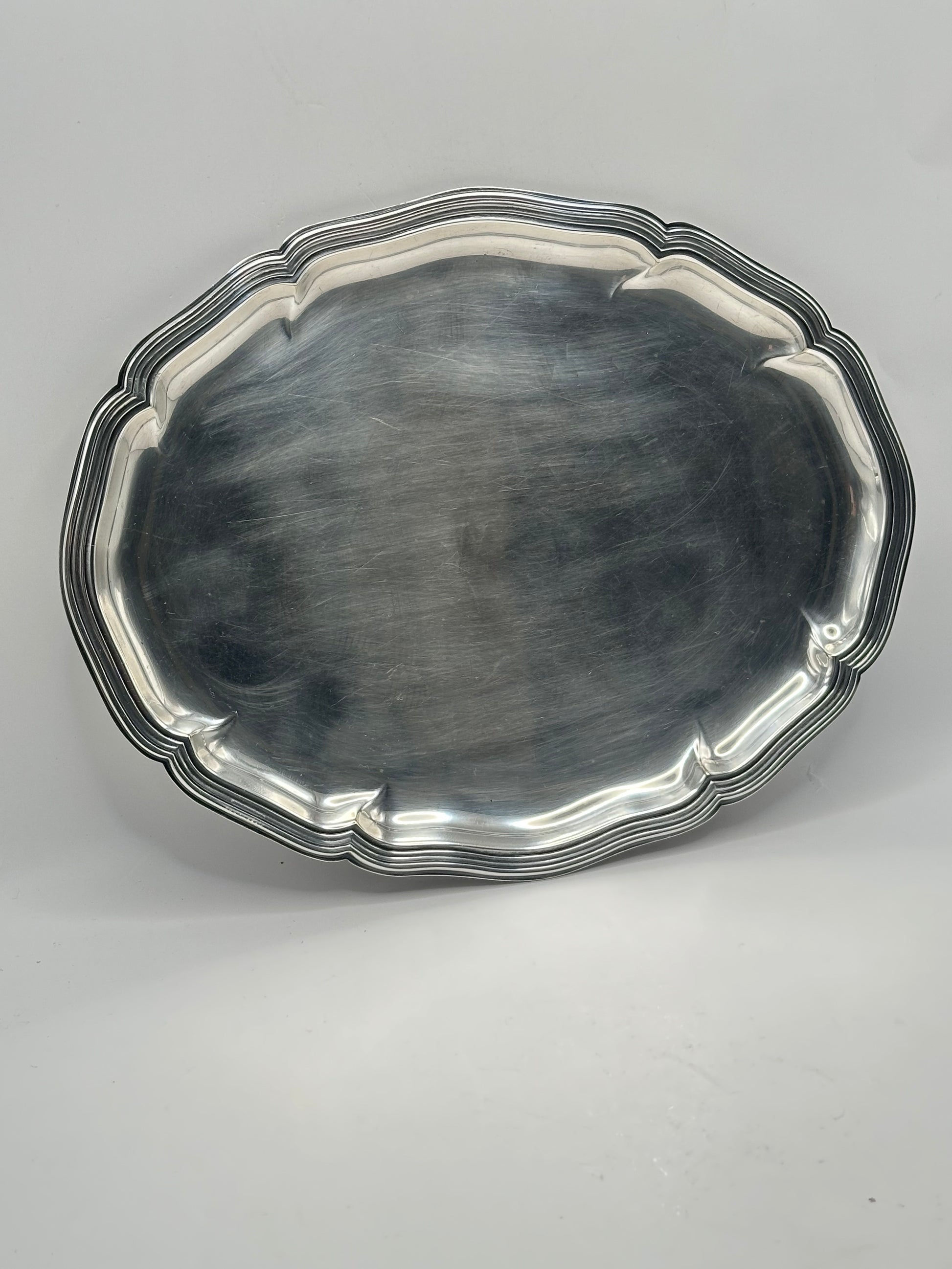 Top-down view of the oval silver-plate tray with its scalloped molded rim