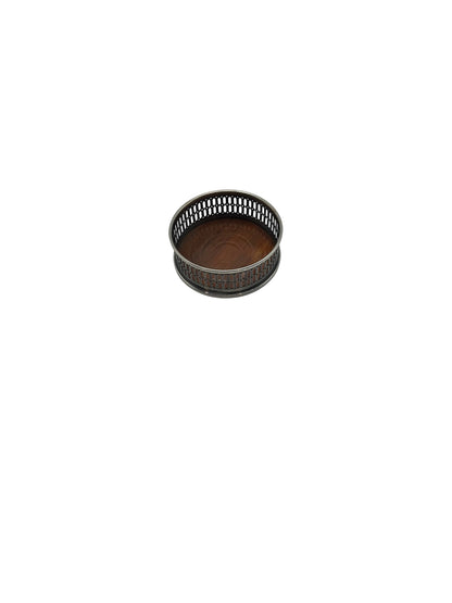 Wine bottle coaster from above at an angle, with pierced silver rim and wood base