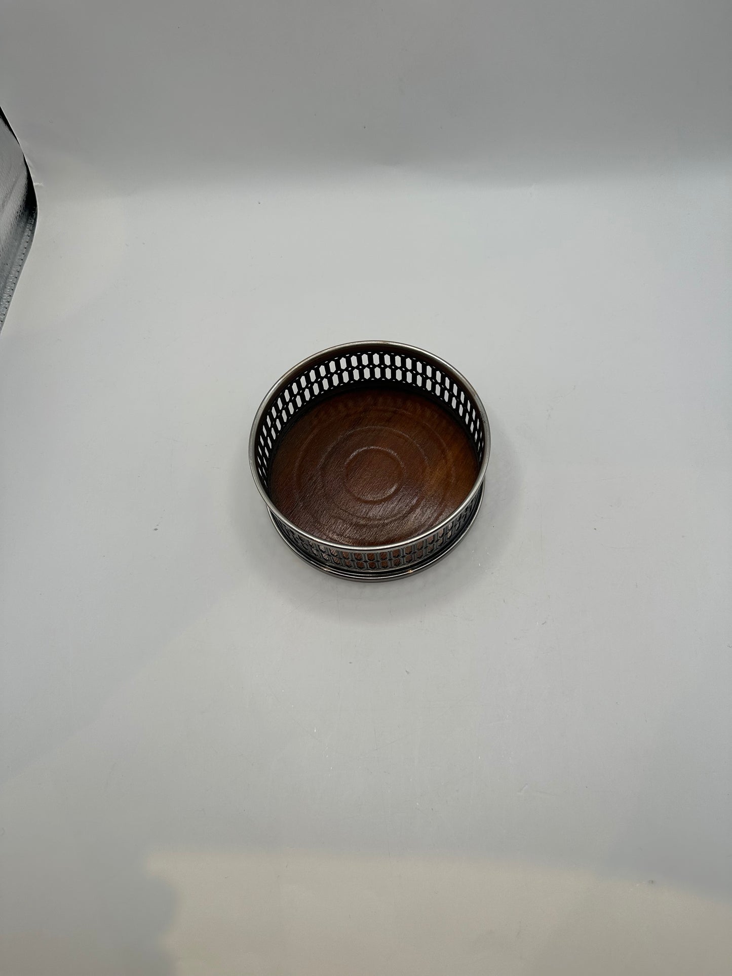 Angled top view of the wine coaster showing the pierced rim and wood base
