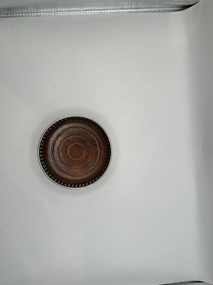 Overhead view of the bottle coaster's turned wood base within the beaded silver rim