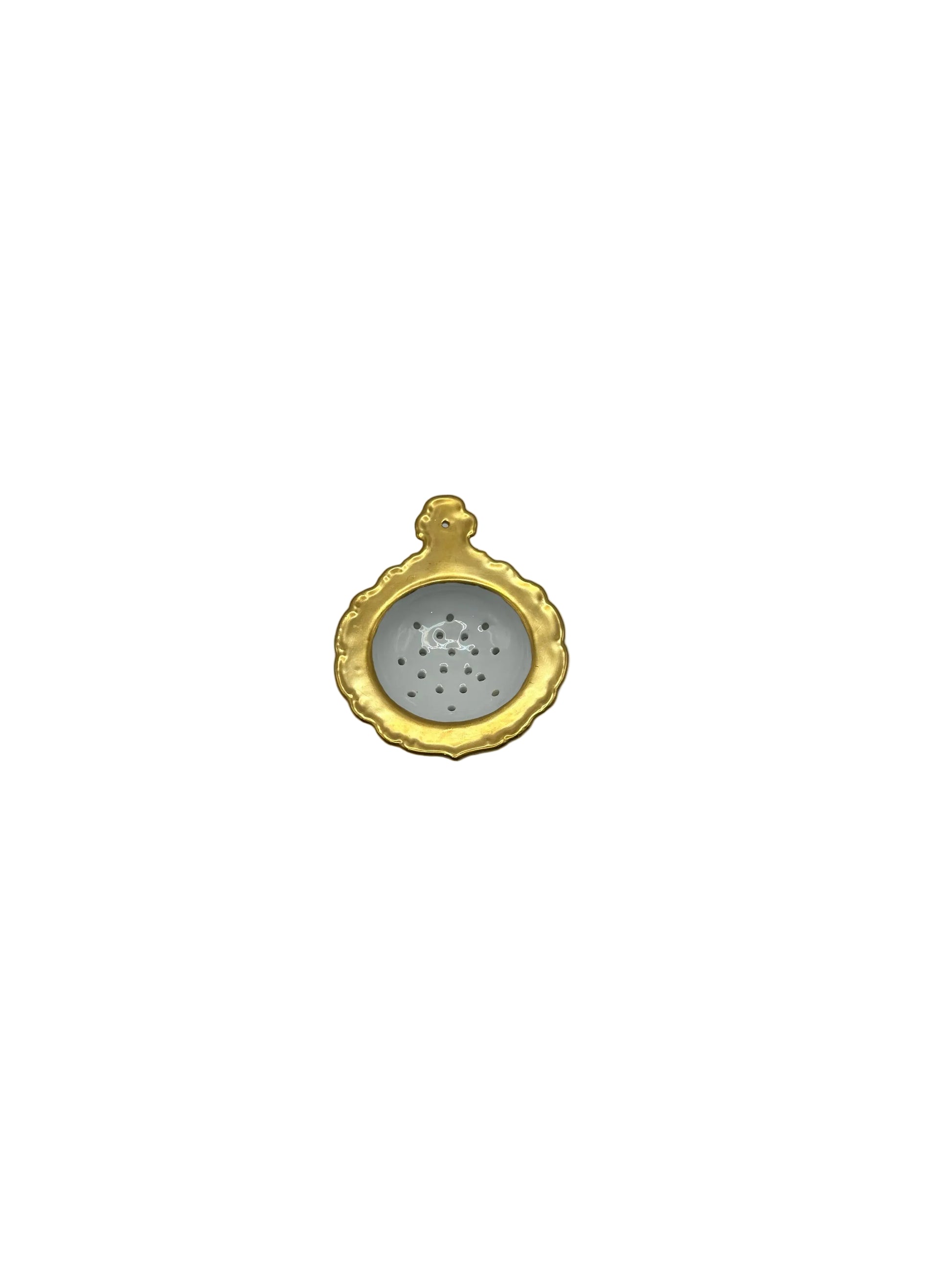 Porcelain tea strainer with a gold scalloped rim, top-down view into the perforated bowl