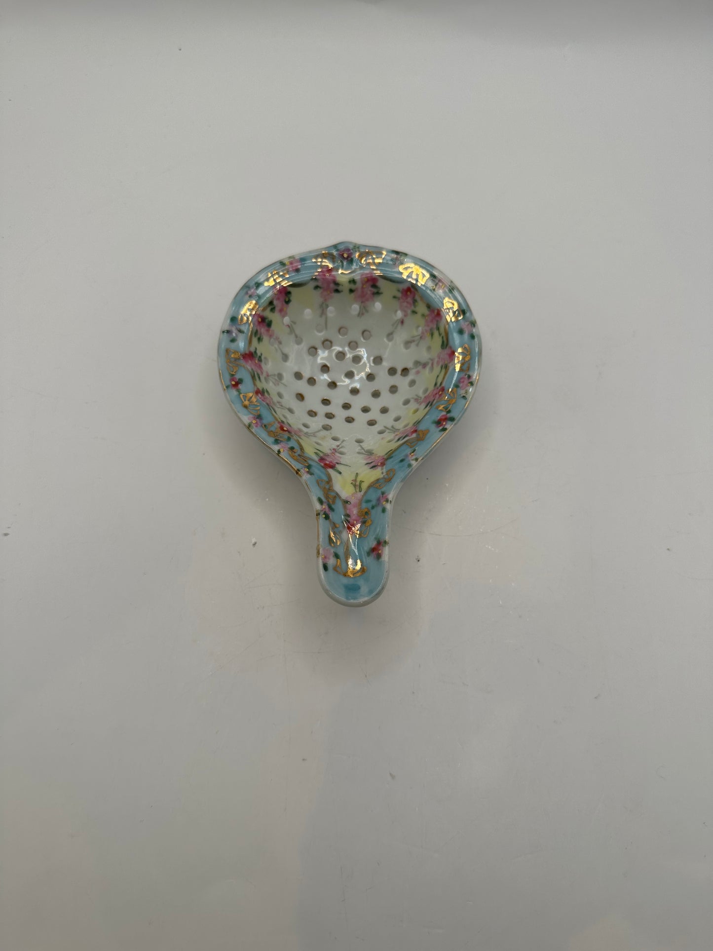 Top-down view into the floral porcelain tea strainer's perforated bowl
