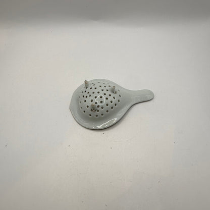 Underside of the porcelain tea strainer showing its three small feet and white glaze